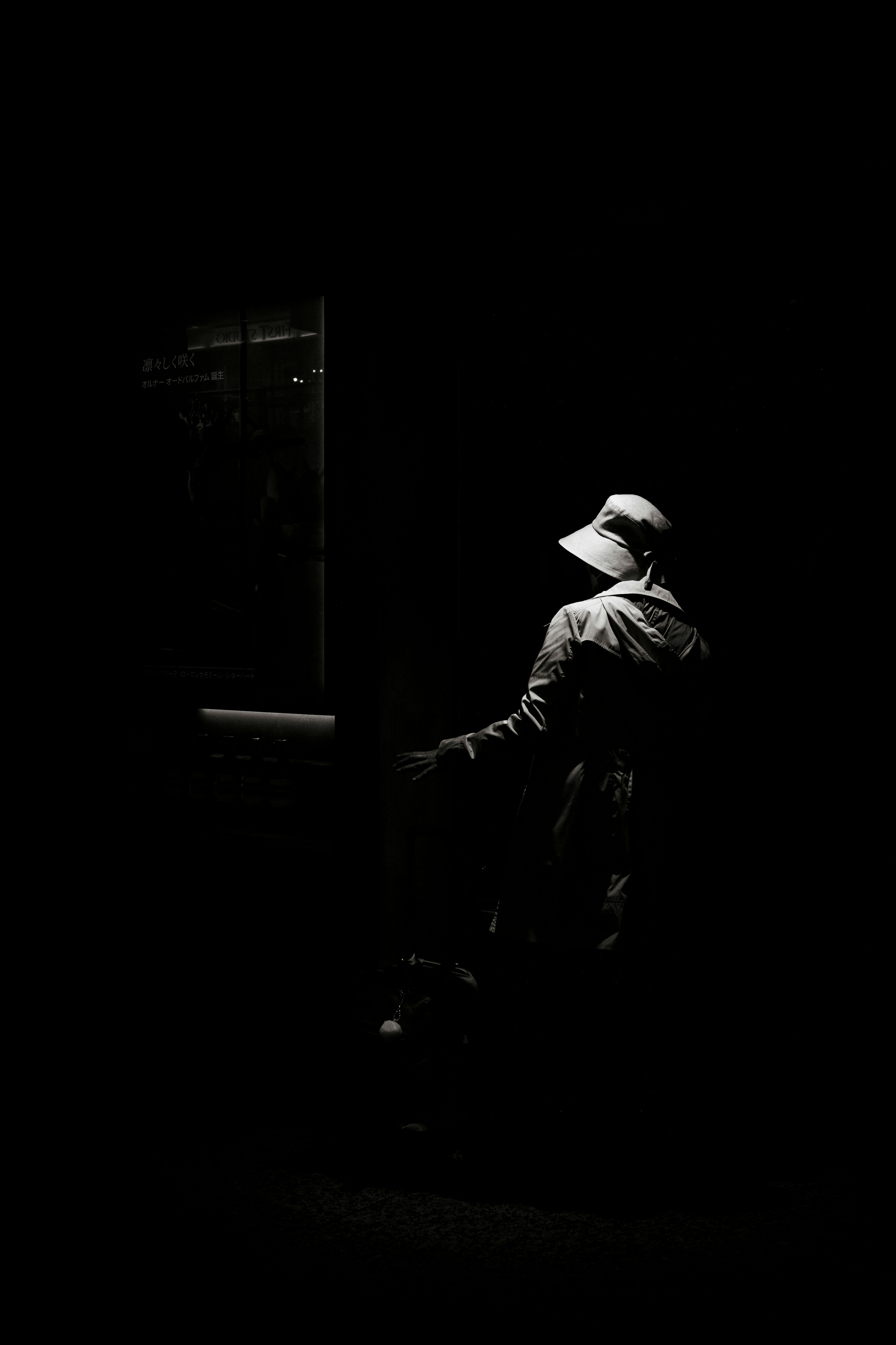 Silhouette of a person wearing a hat standing against a dark background