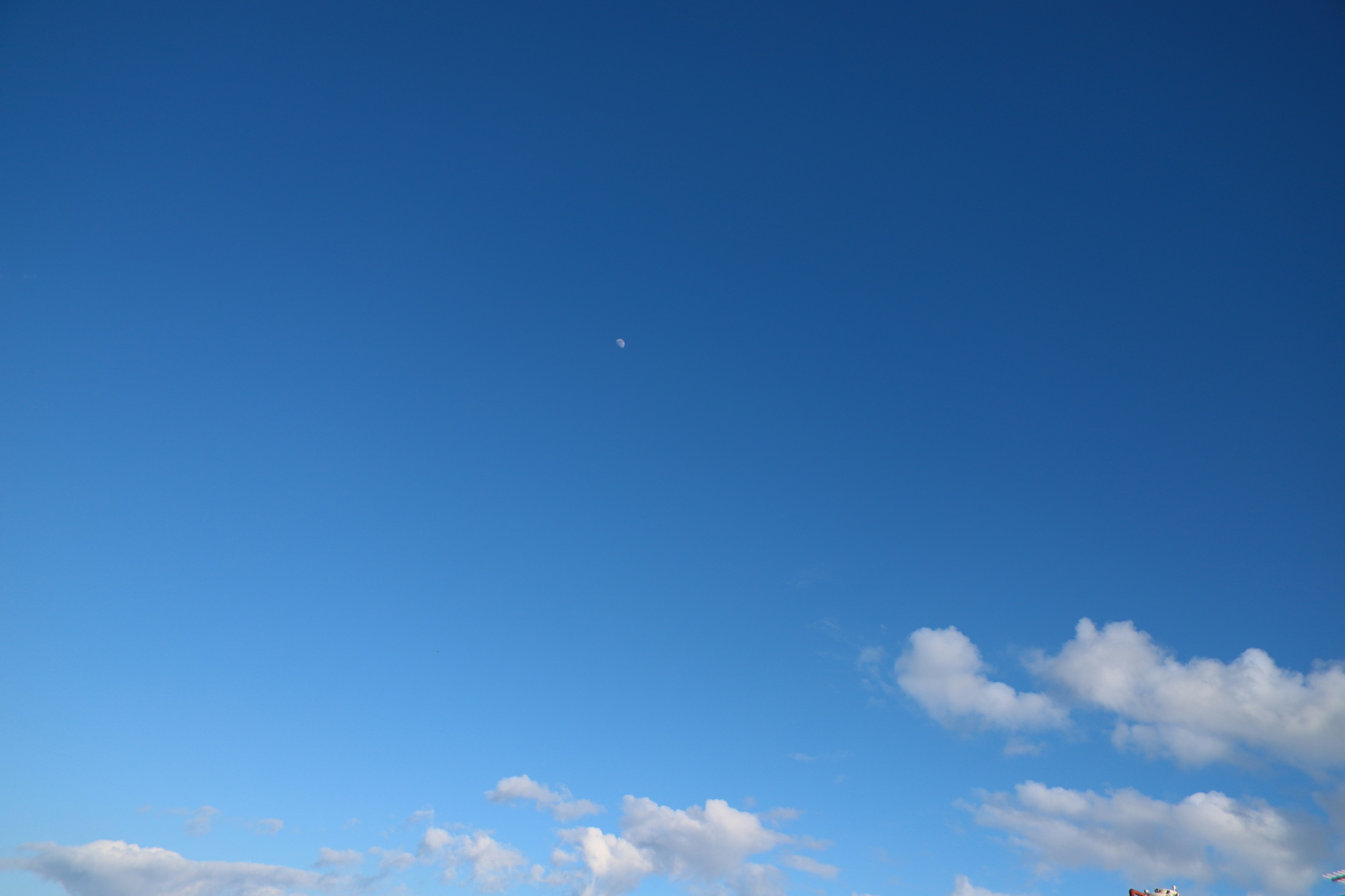 A vast blue sky with white clouds featuring a small object in the distance