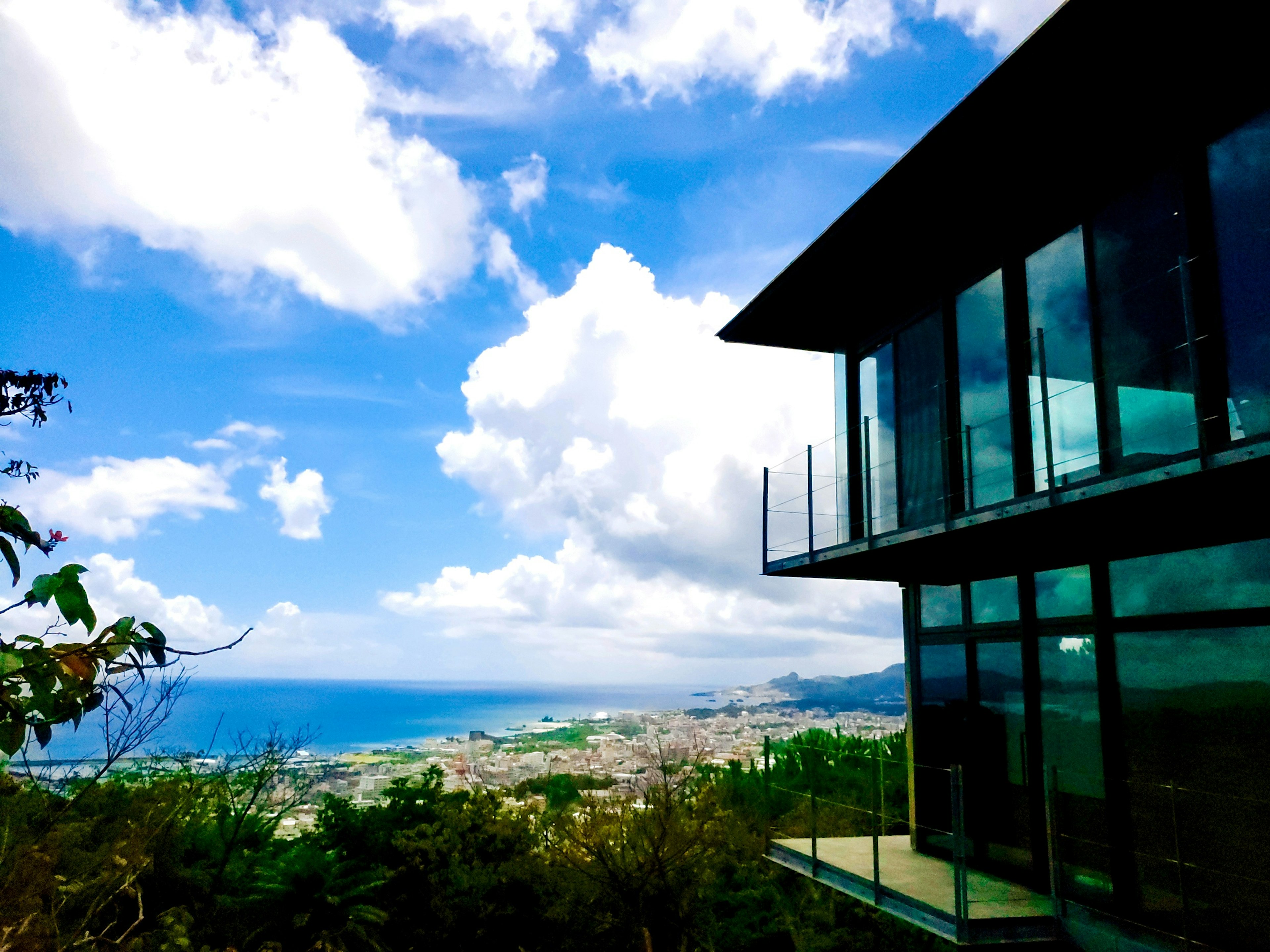 Modern glass house with blue sky and white clouds in the background