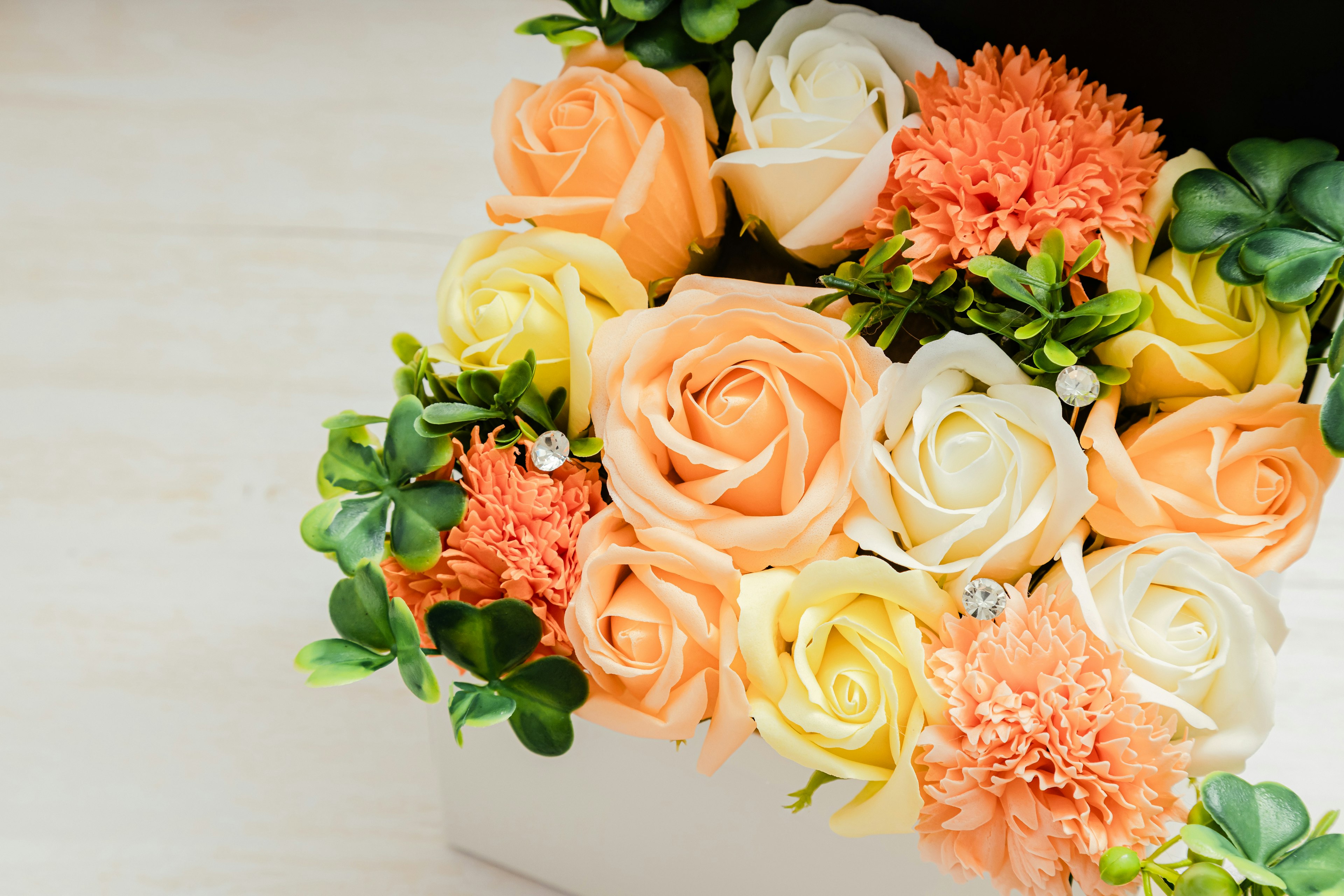 Un bouquet avec des roses pêche et crème et des fleurs orange