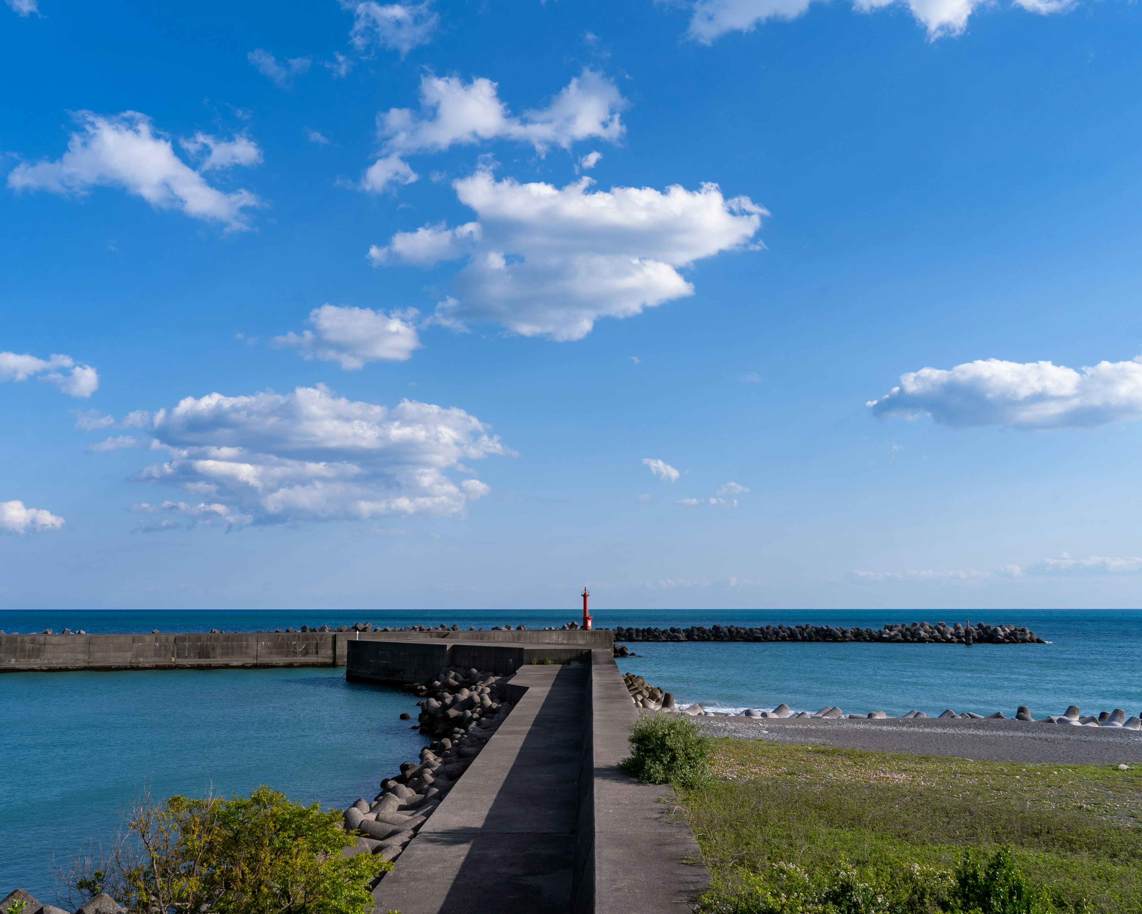 Vista escénica de un espigón que conduce a un mar azul bajo un cielo parcialmente nublado