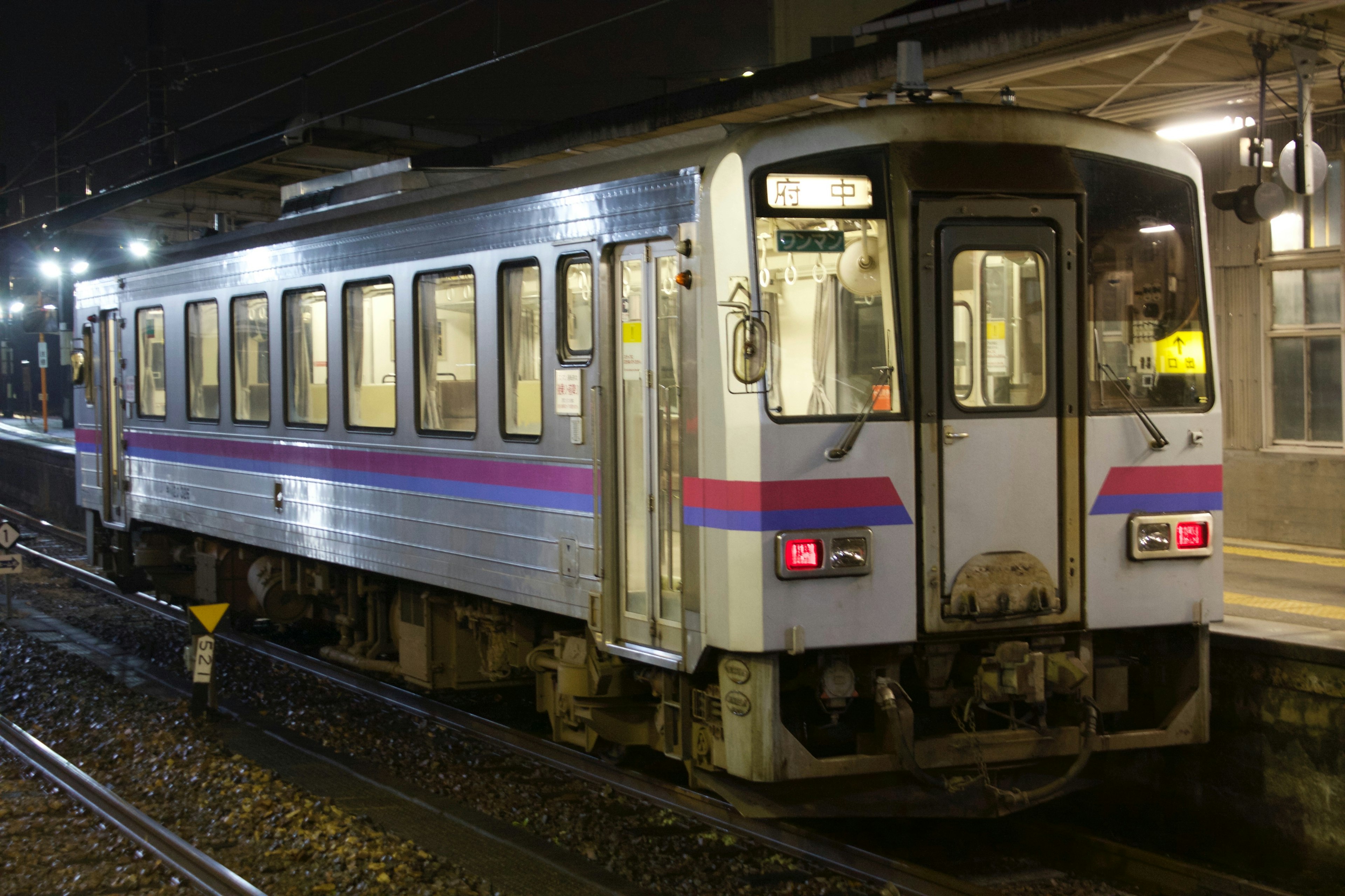 Vagón de tren en una estación durante la noche con ventanas iluminadas