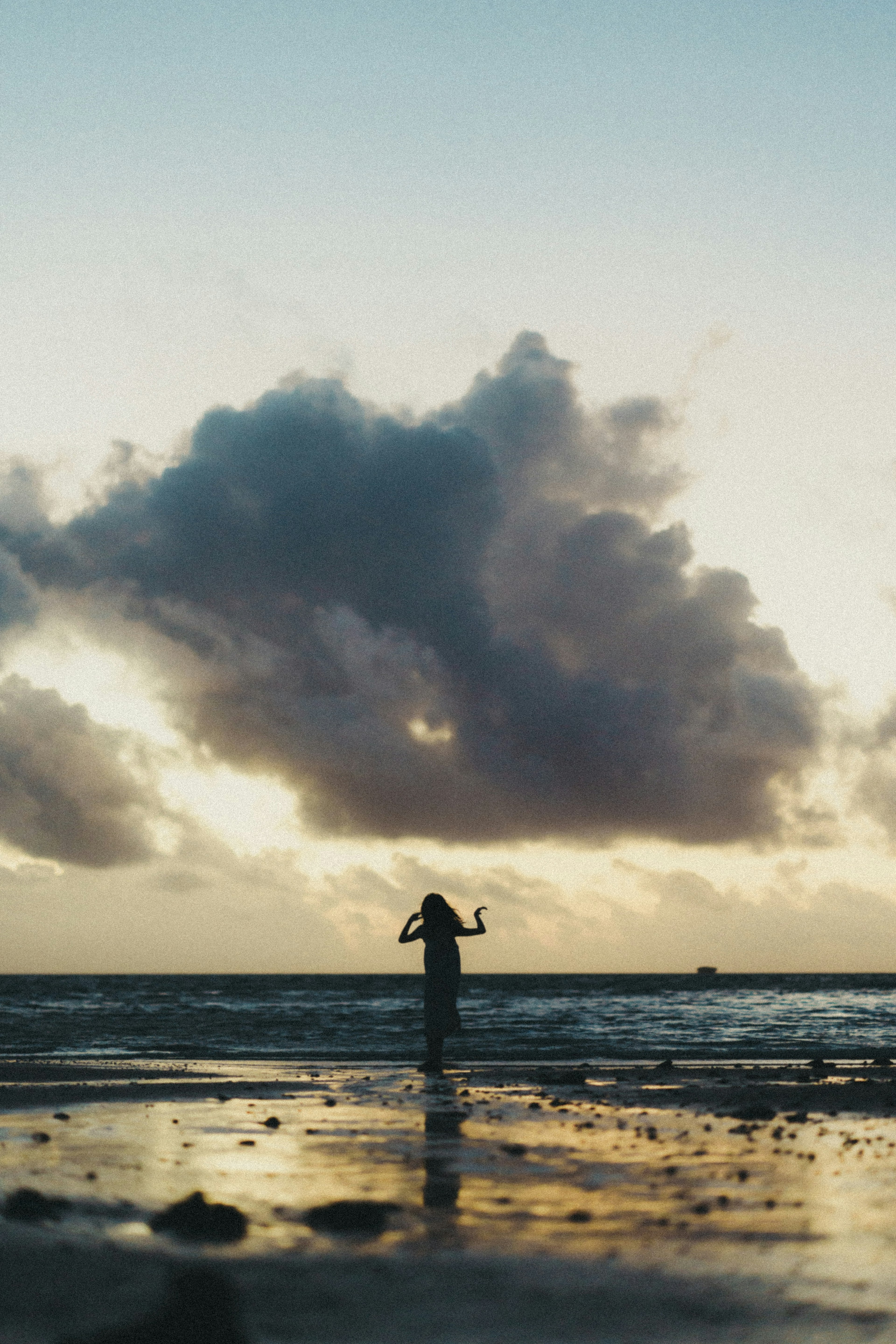 Silhouette d'une femme debout dans l'océan au coucher du soleil