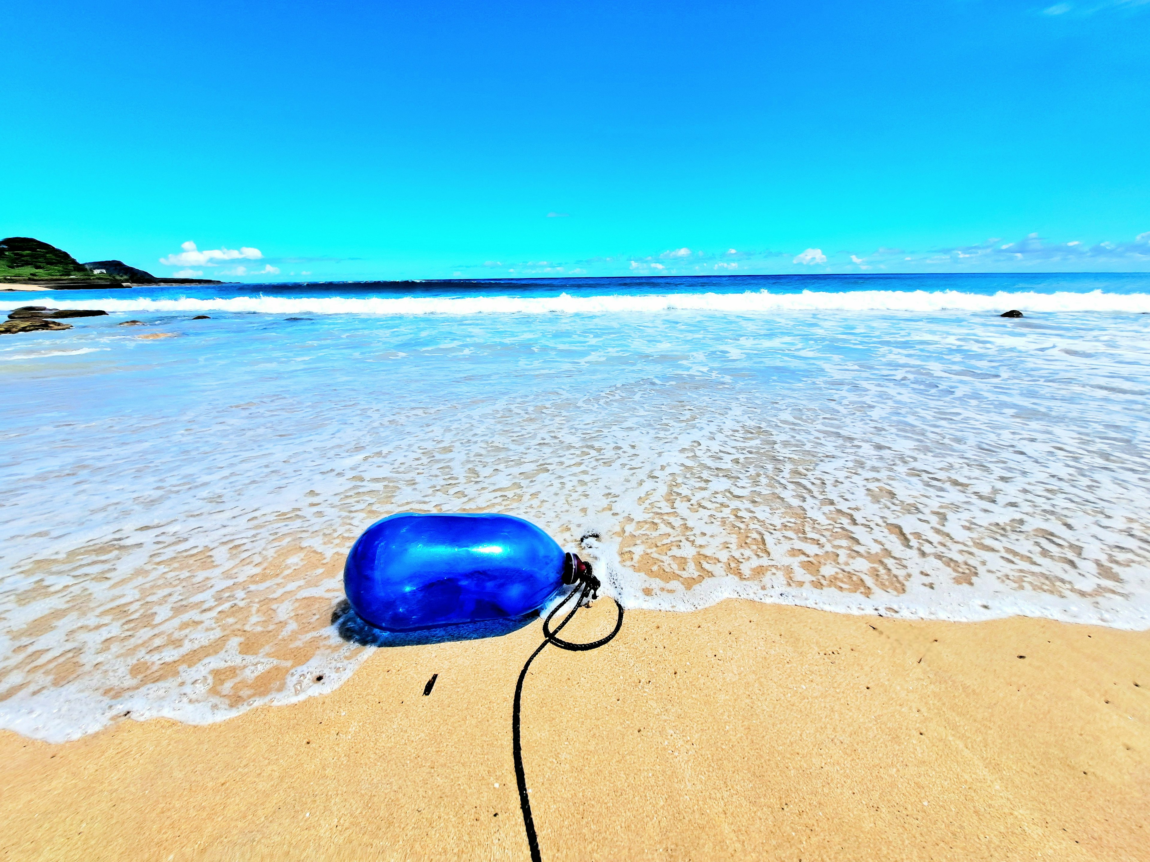 Blaue Boje am Sandstrand mit Ozeanwellen