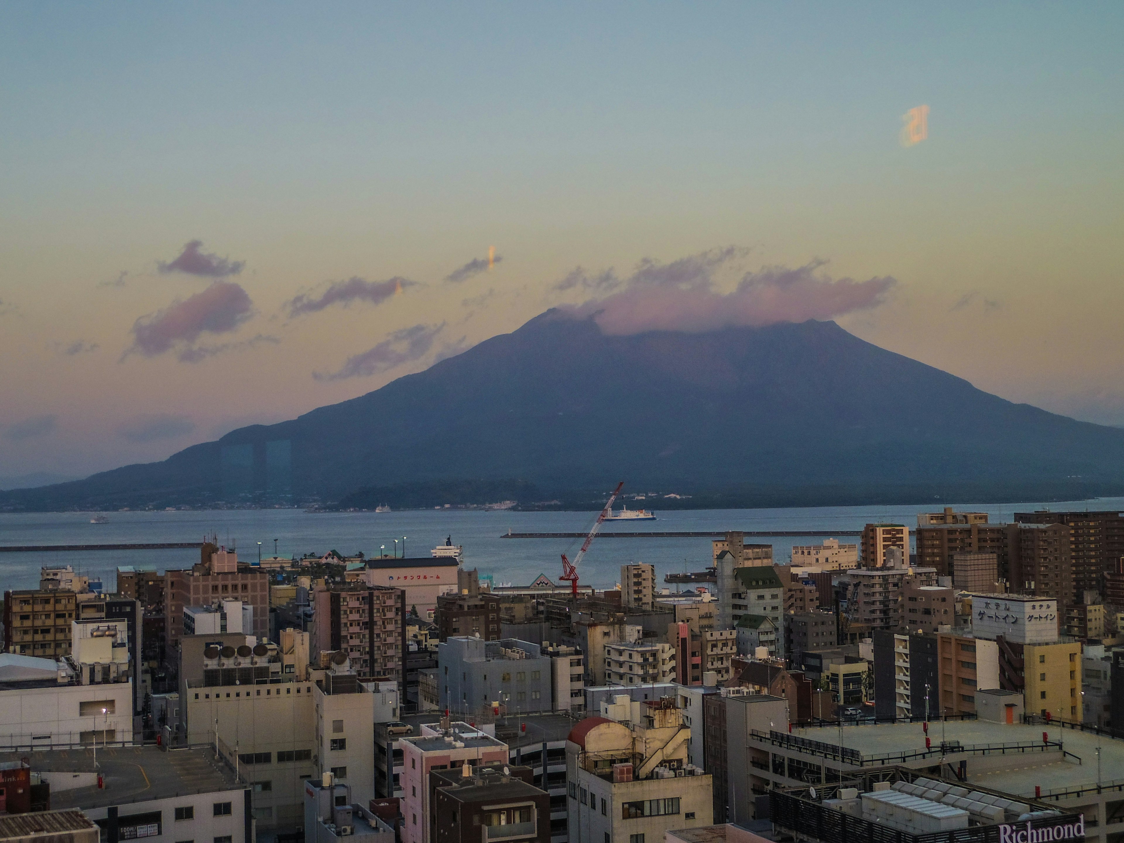 Blick auf die Stadt Kagoshima mit Sakurajima bei Sonnenuntergang