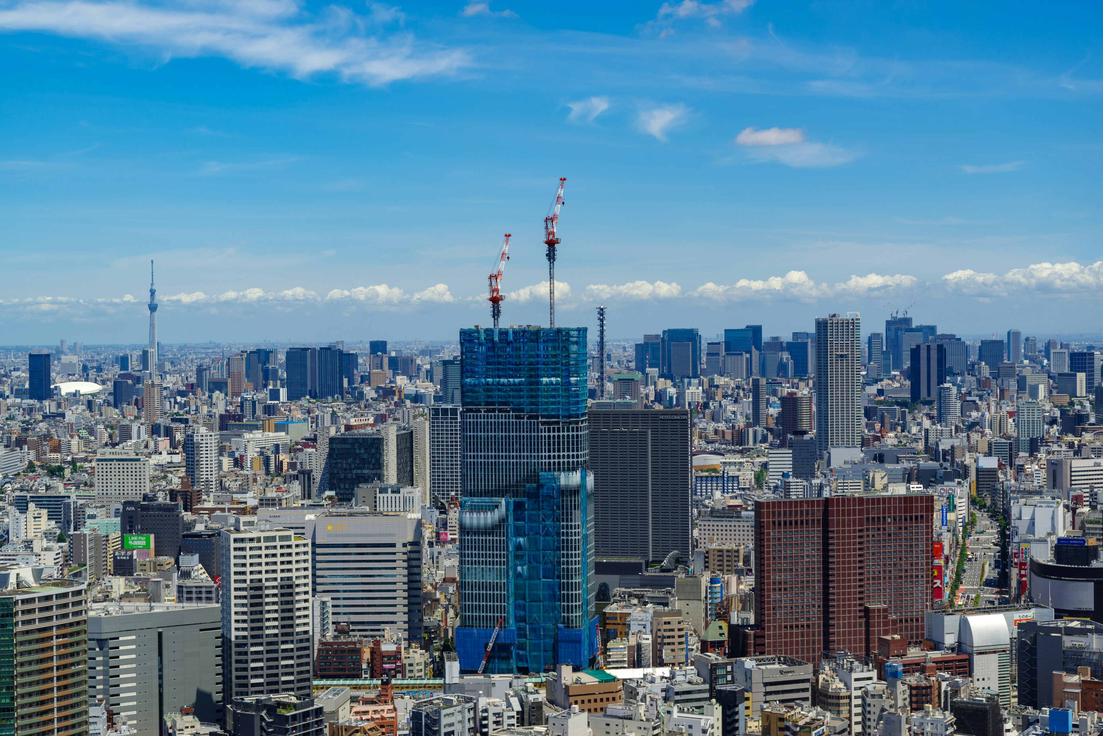 Cảnh quan toàn cảnh của đường chân trời Tokyo với một tòa nhà chọc trời màu xanh nổi bật dưới bầu trời xanh trong vắt