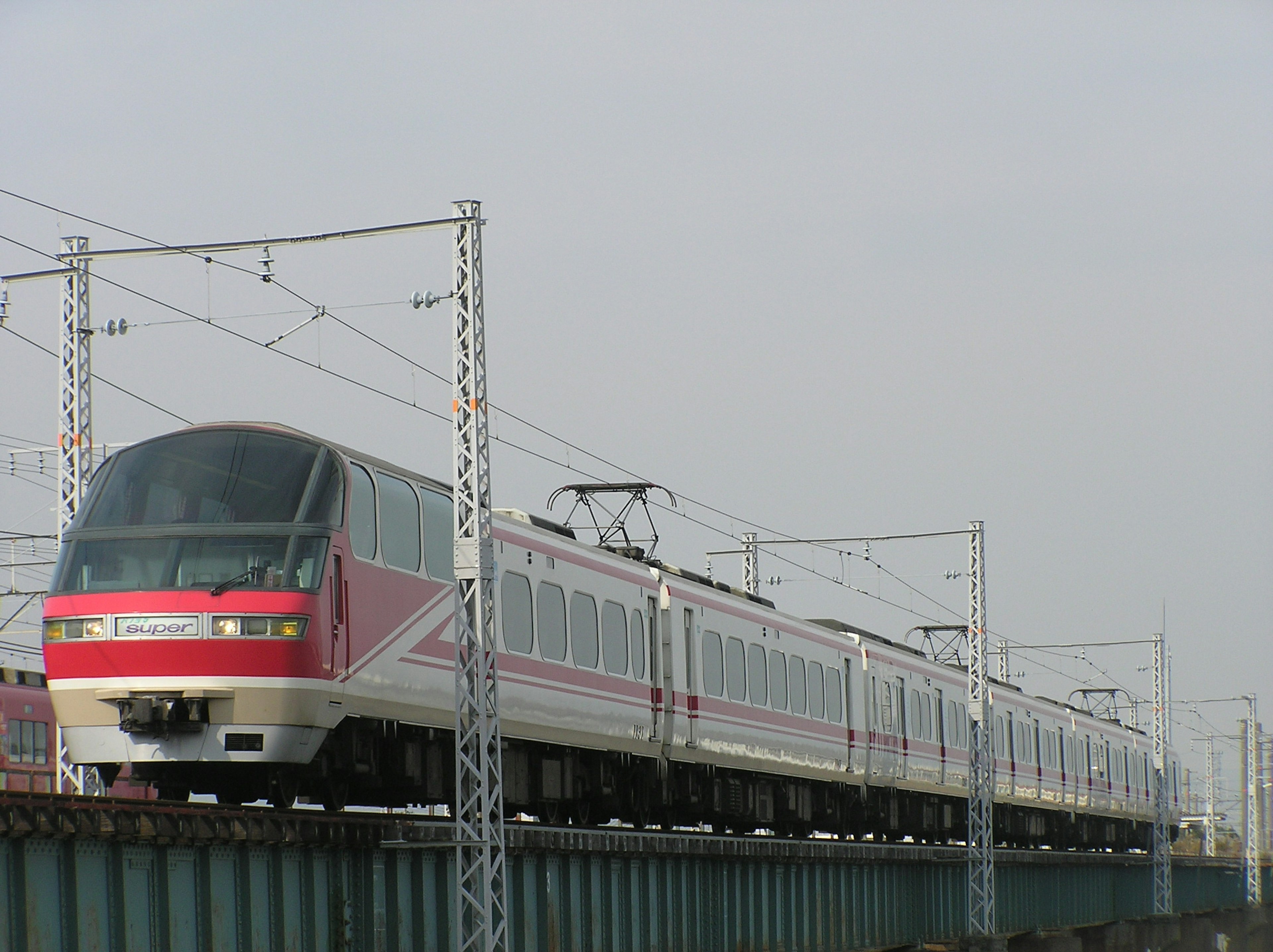 A red and white train traveling on an elevated railway