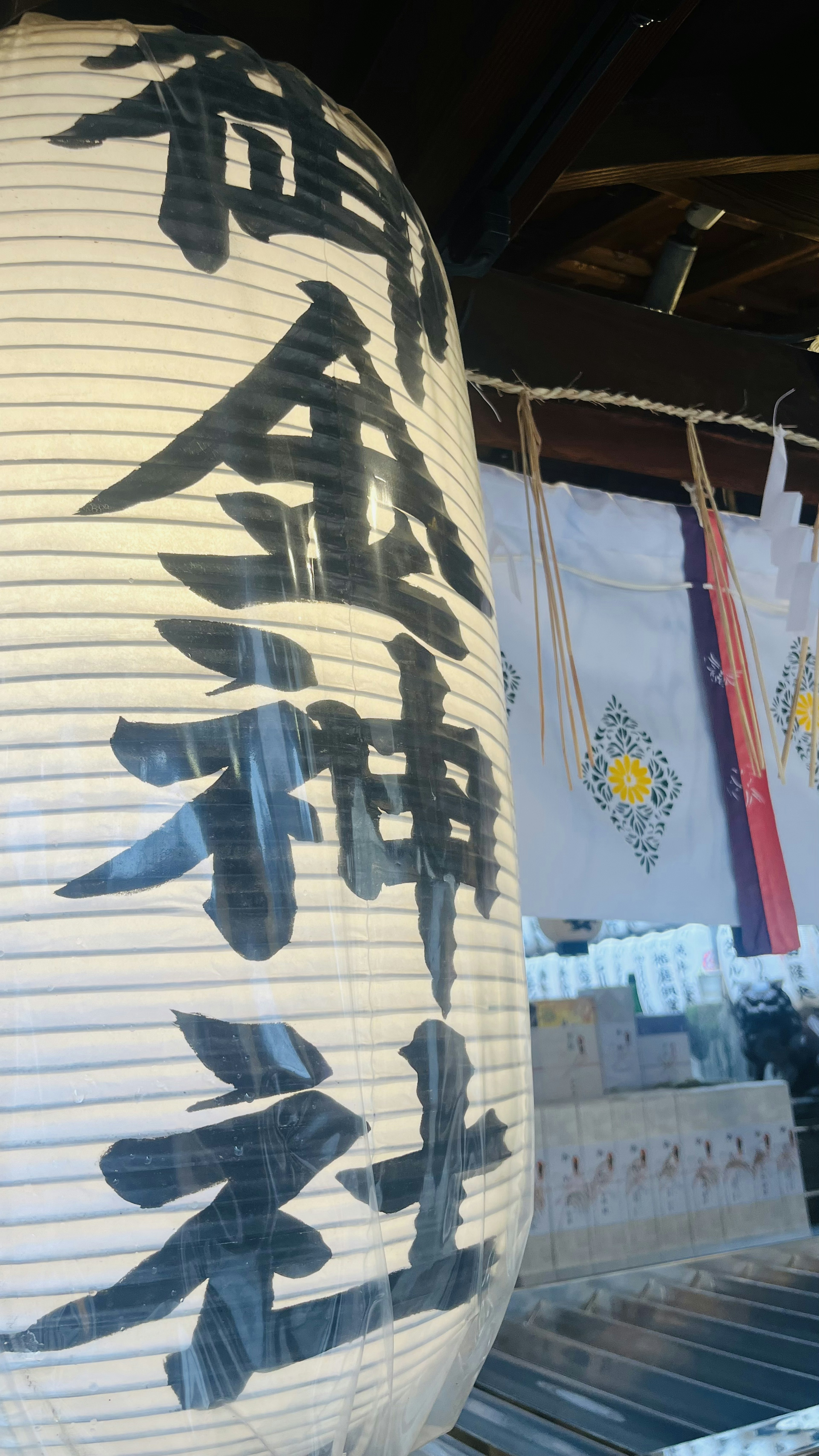 Large lantern at a shrine with bold calligraphy and decorative shimenawa