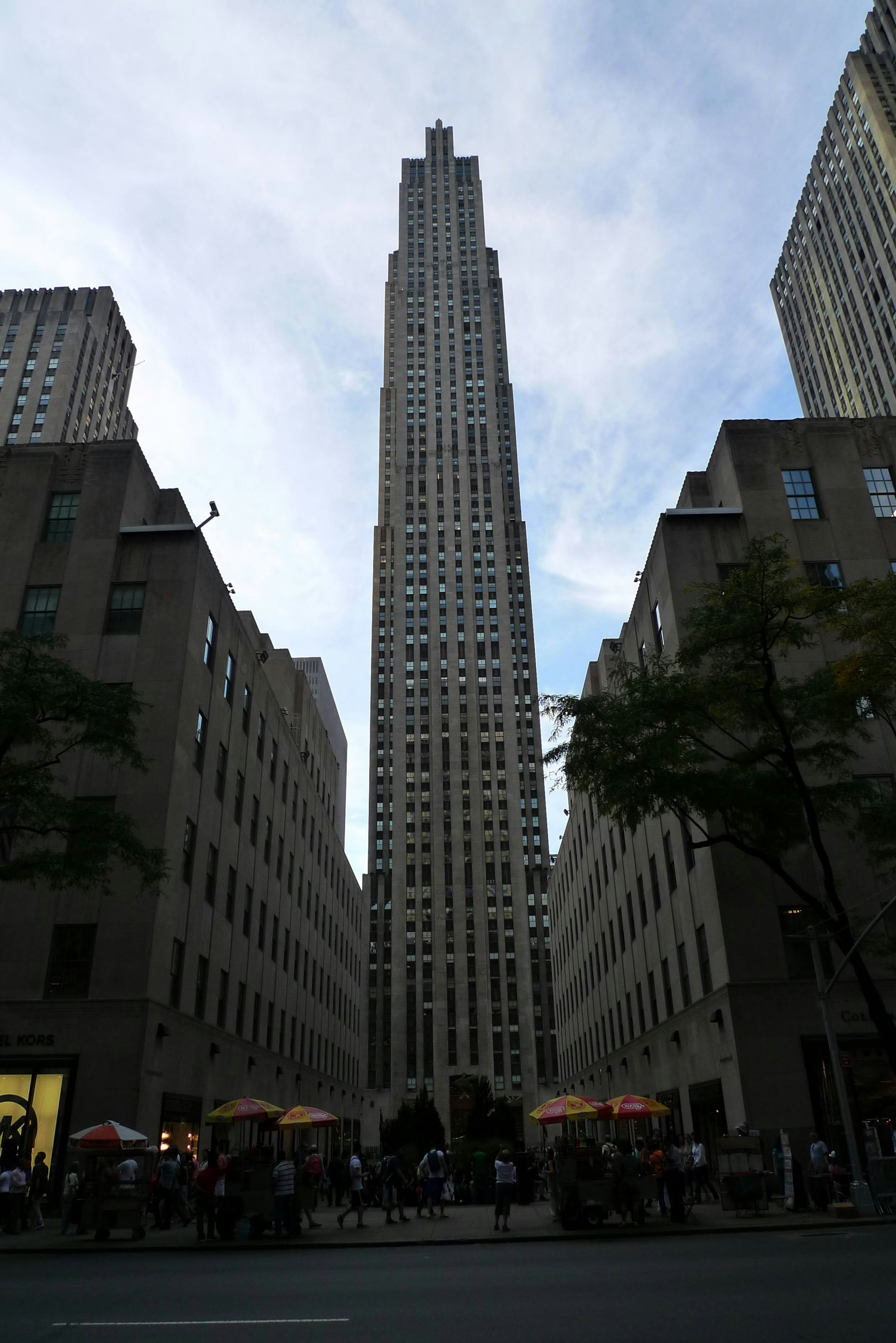 Tall skyscraper under a blue sky with people gathered at the base