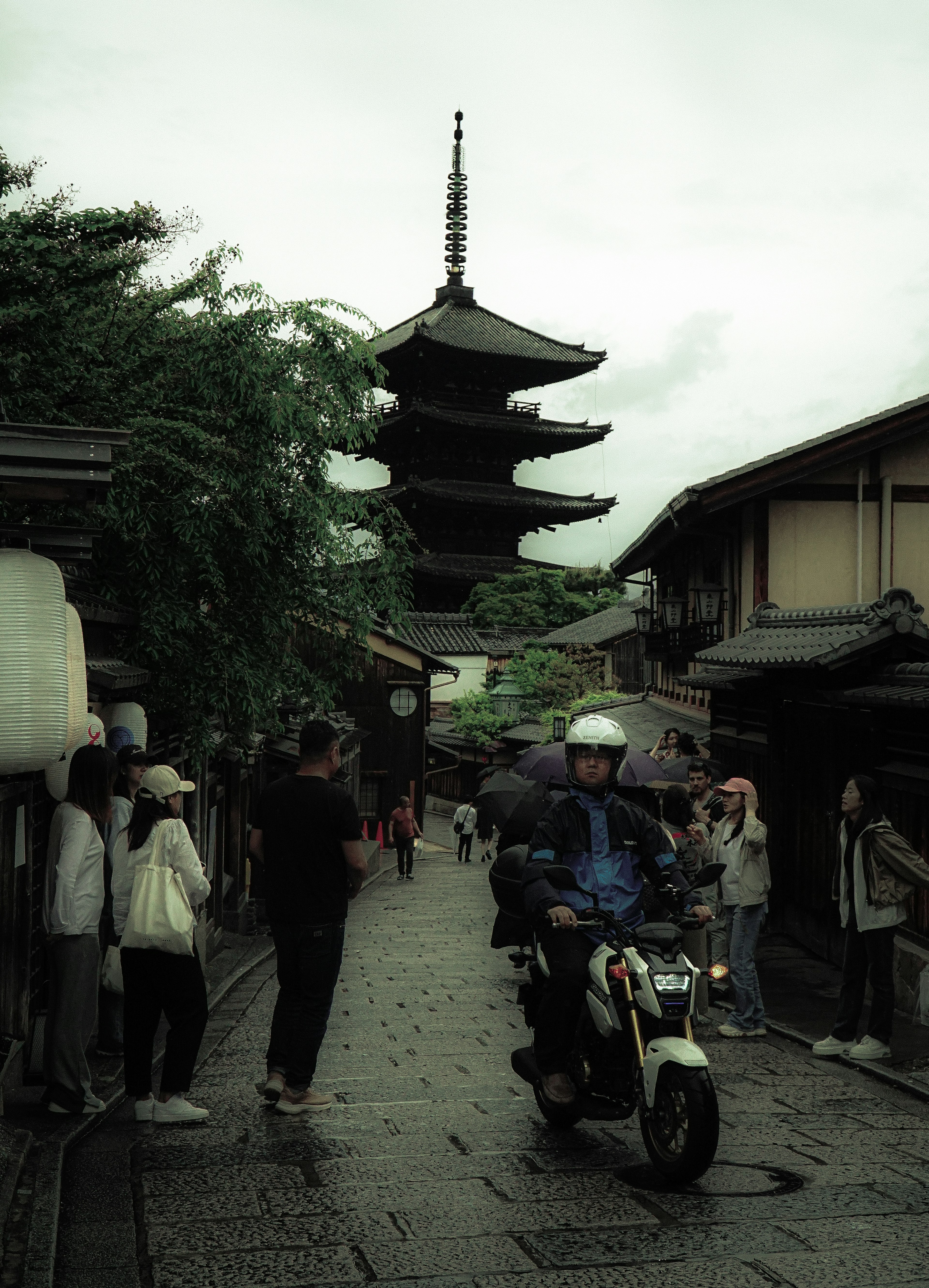 Motocicleta pasando por una calle histórica con una pagoda al fondo