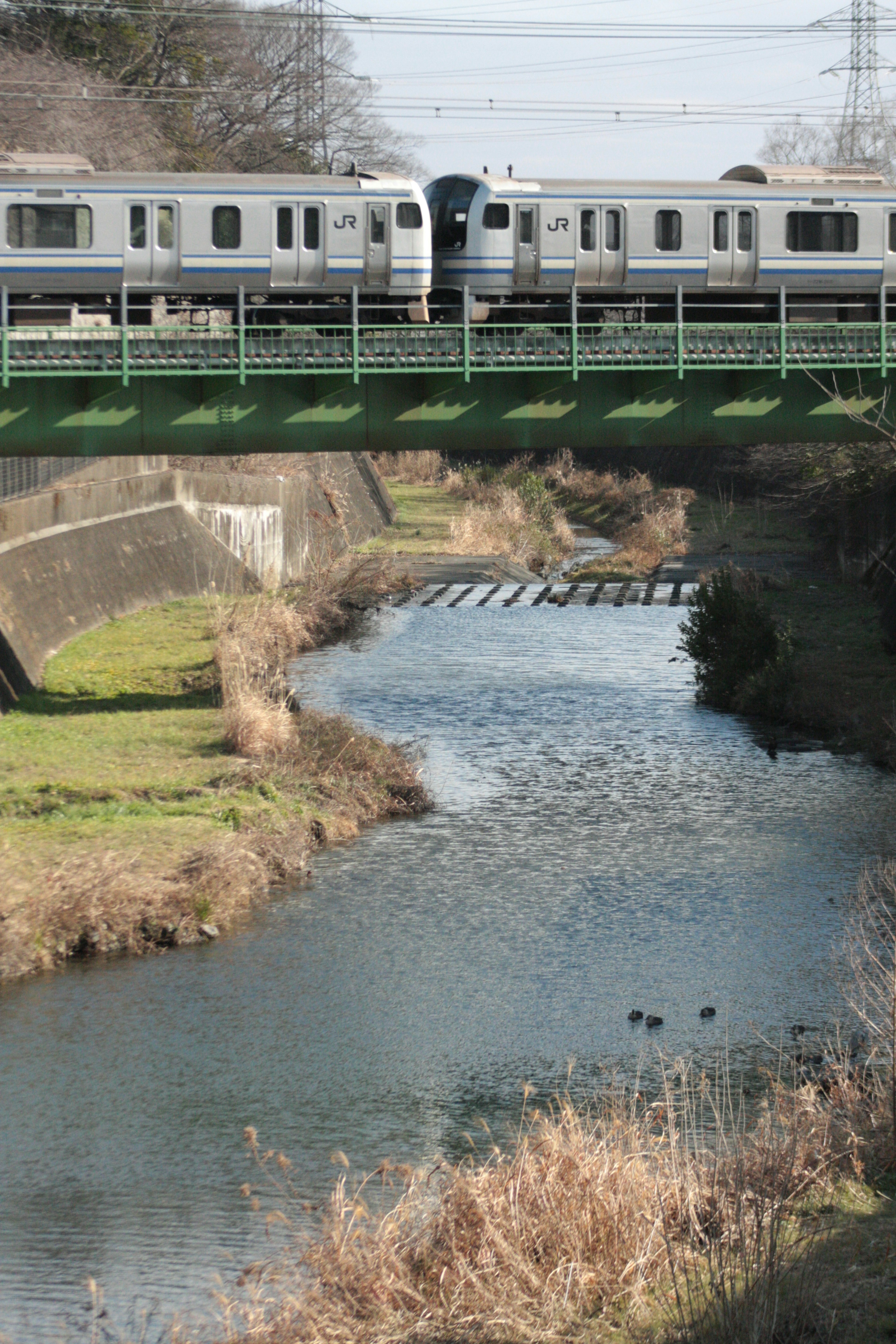 Train crossing a bridge over a river with natural scenery