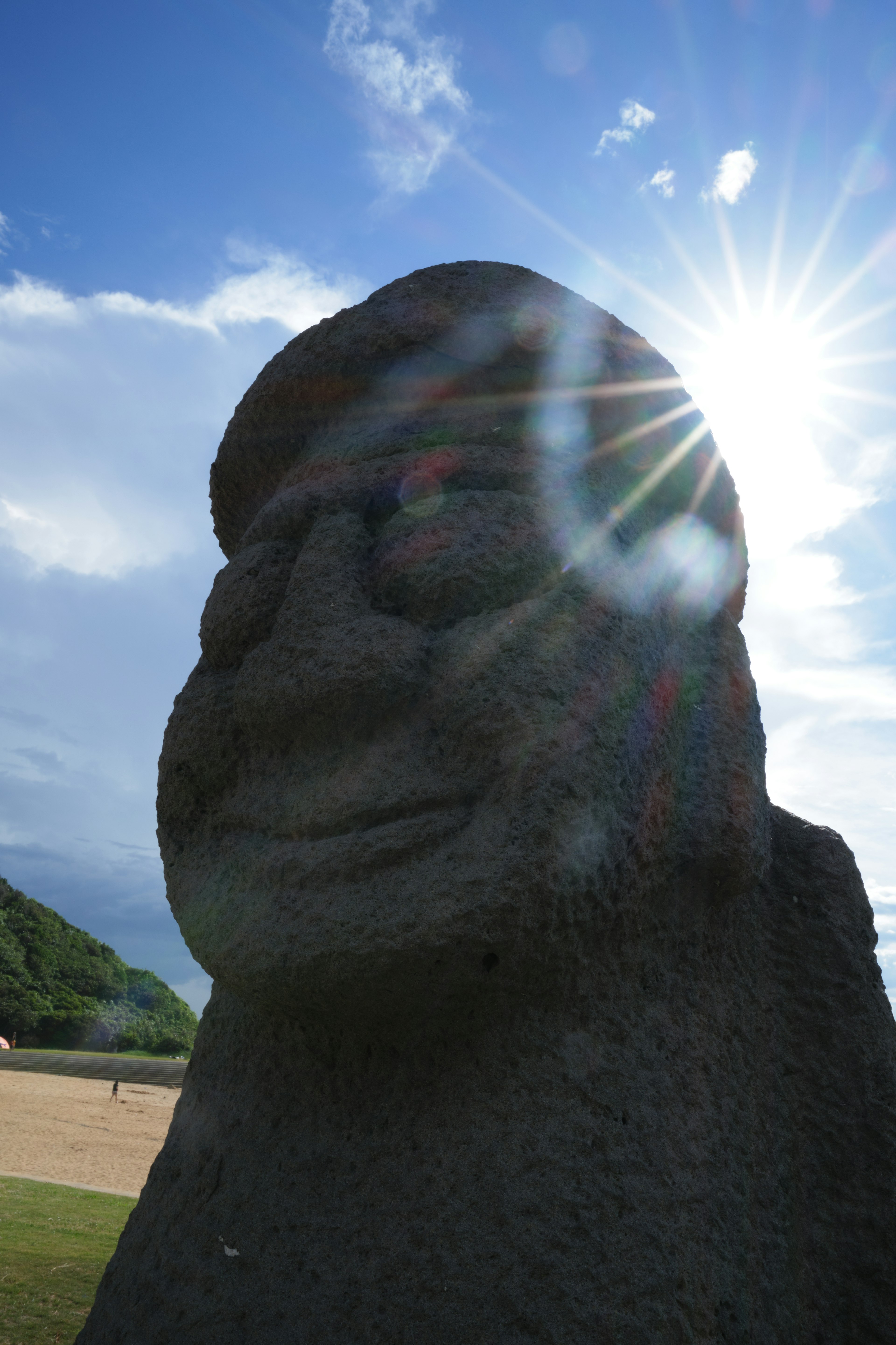 Primo piano di una statua in pietra illuminata dal sole con cielo blu e nuvole sullo sfondo