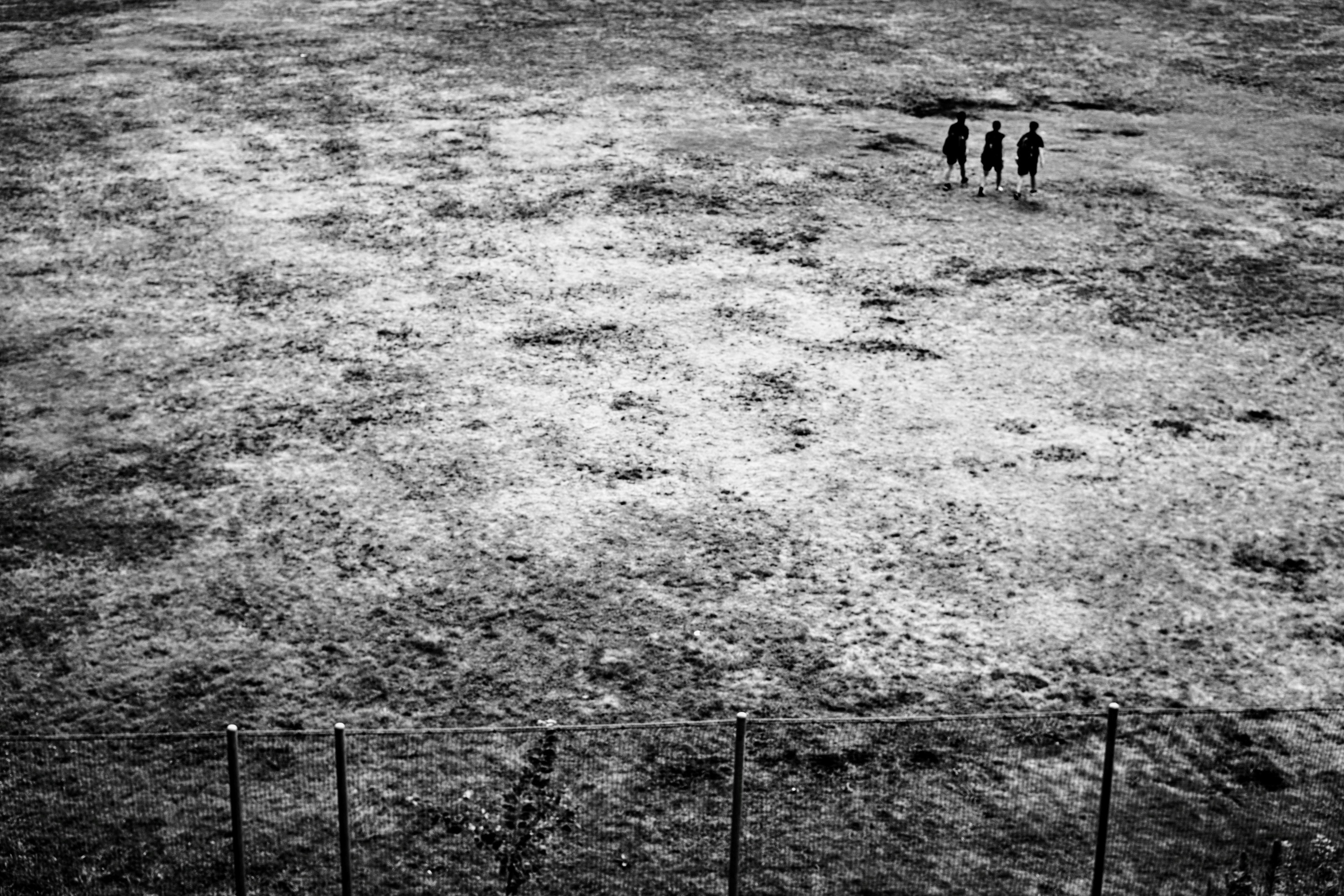 Trois silhouettes debout sur un vaste champ stérile