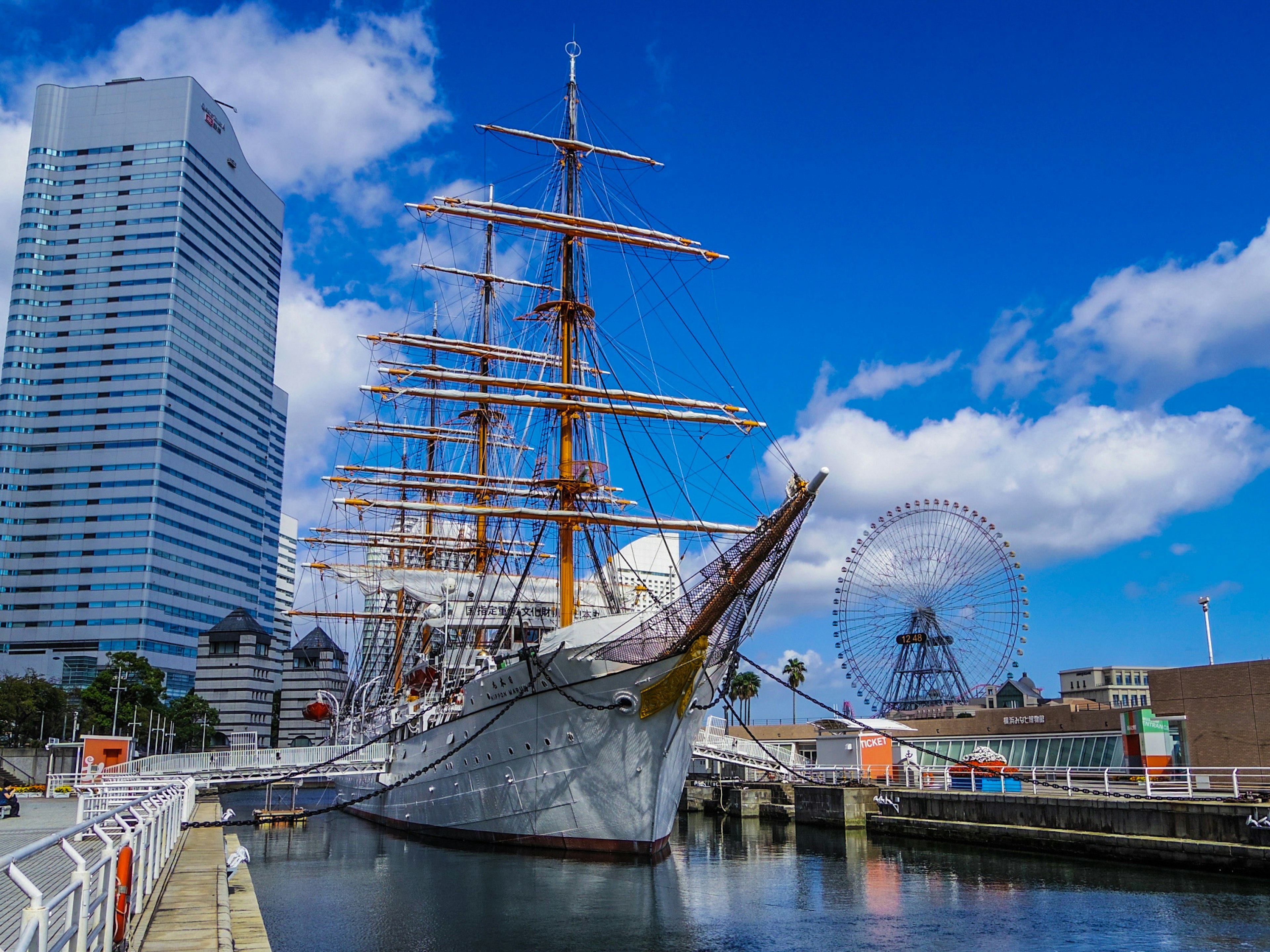 Una grande nave a vela ormeggiata in un porto con grattacieli e cielo azzurro sullo sfondo