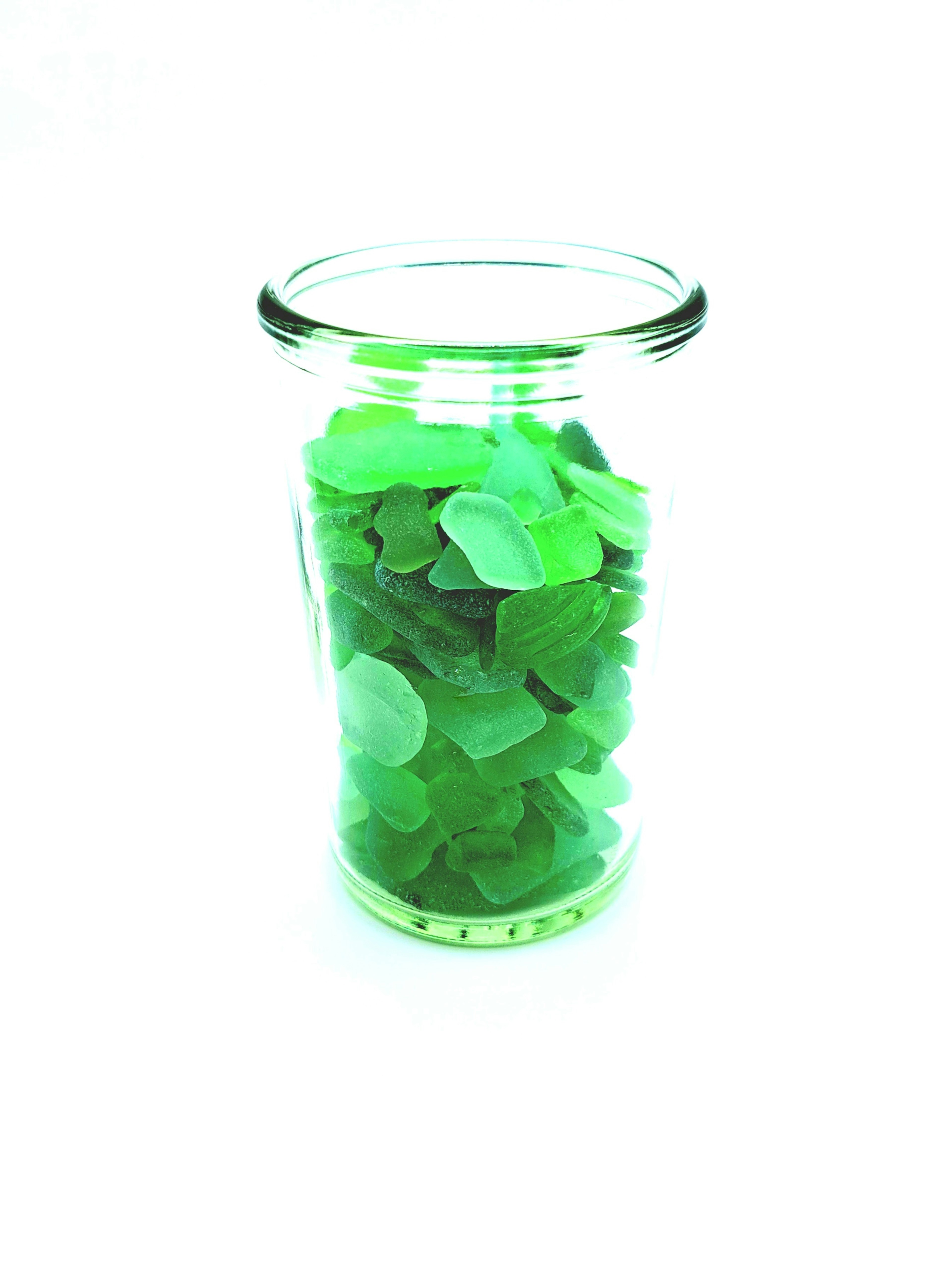 A clear glass jar filled with green sea glass