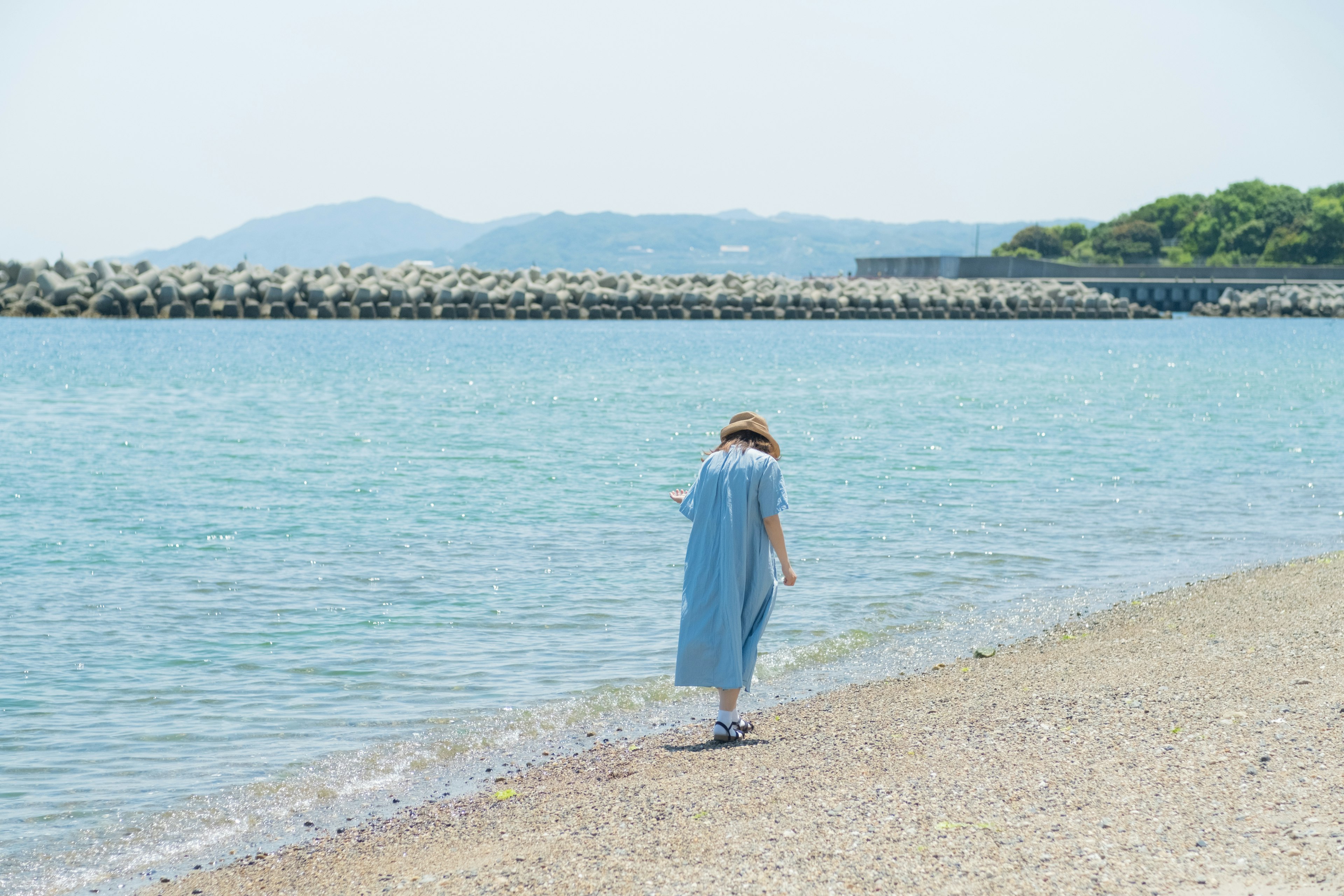 Una donna in abito blu che cammina lungo la spiaggia