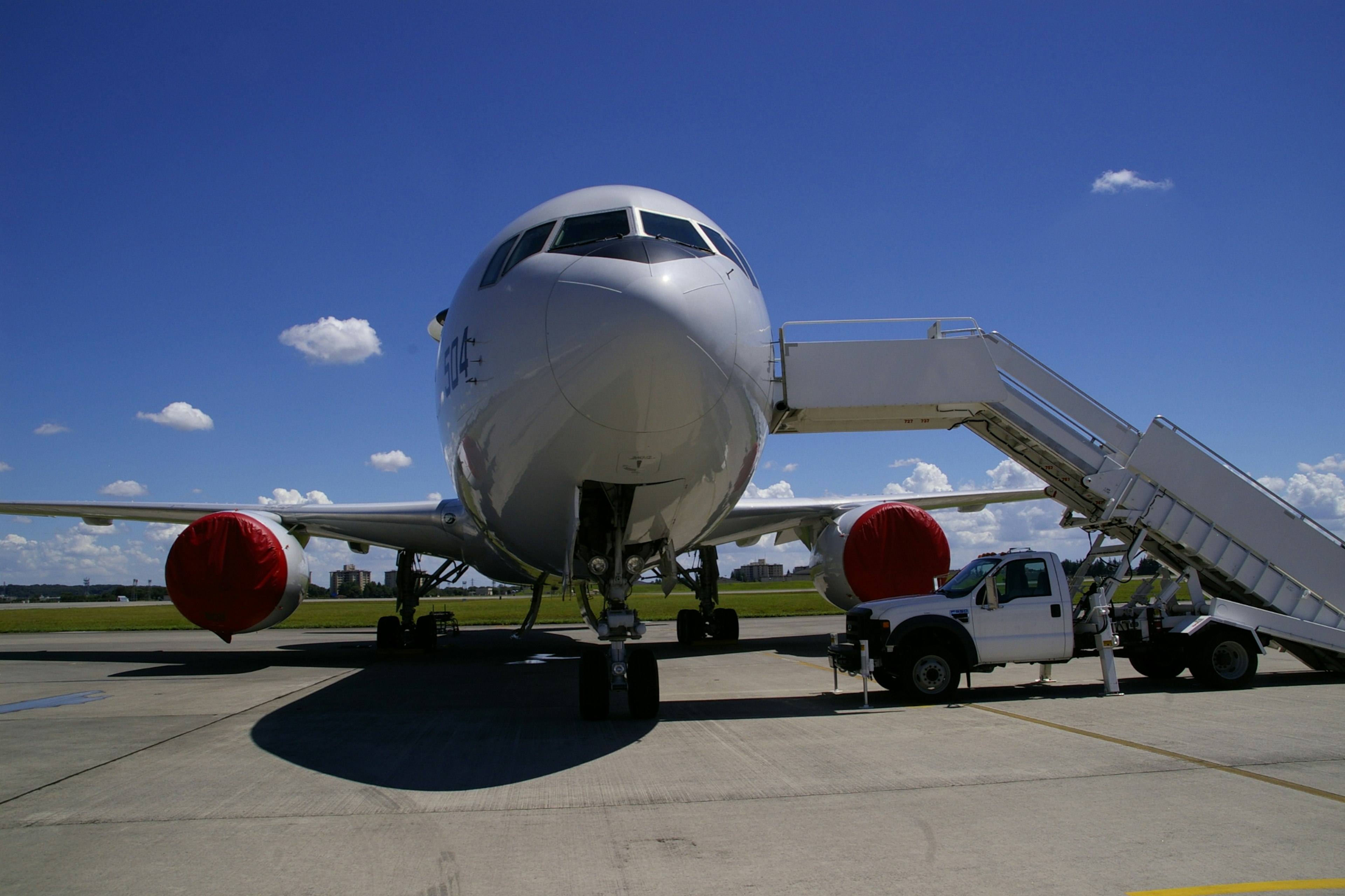 Vista frontal de un gran avión de pasajeros en la pista con una escalera de embarque