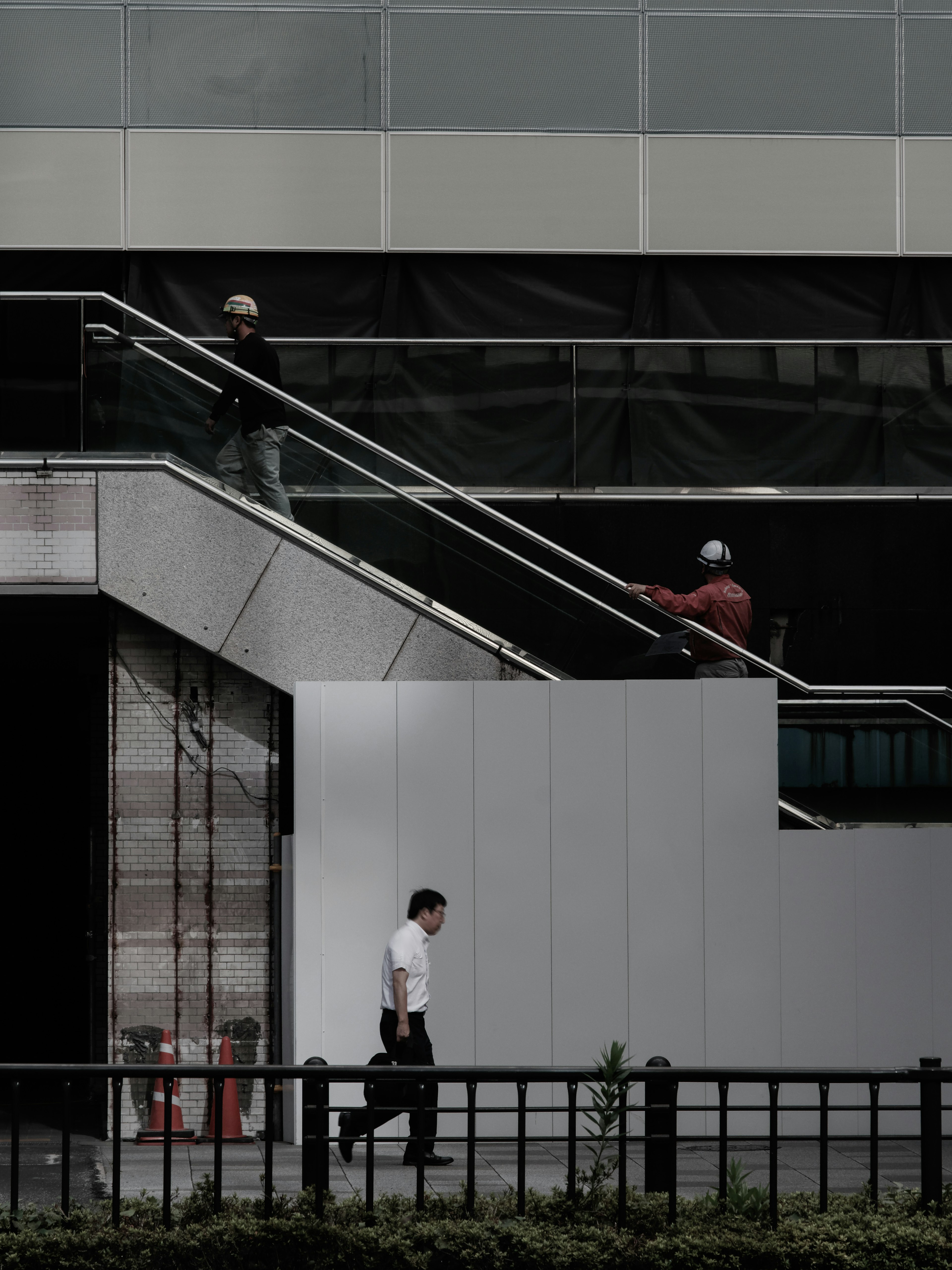 Photo de deux travailleurs et d'un passant devant un bâtiment