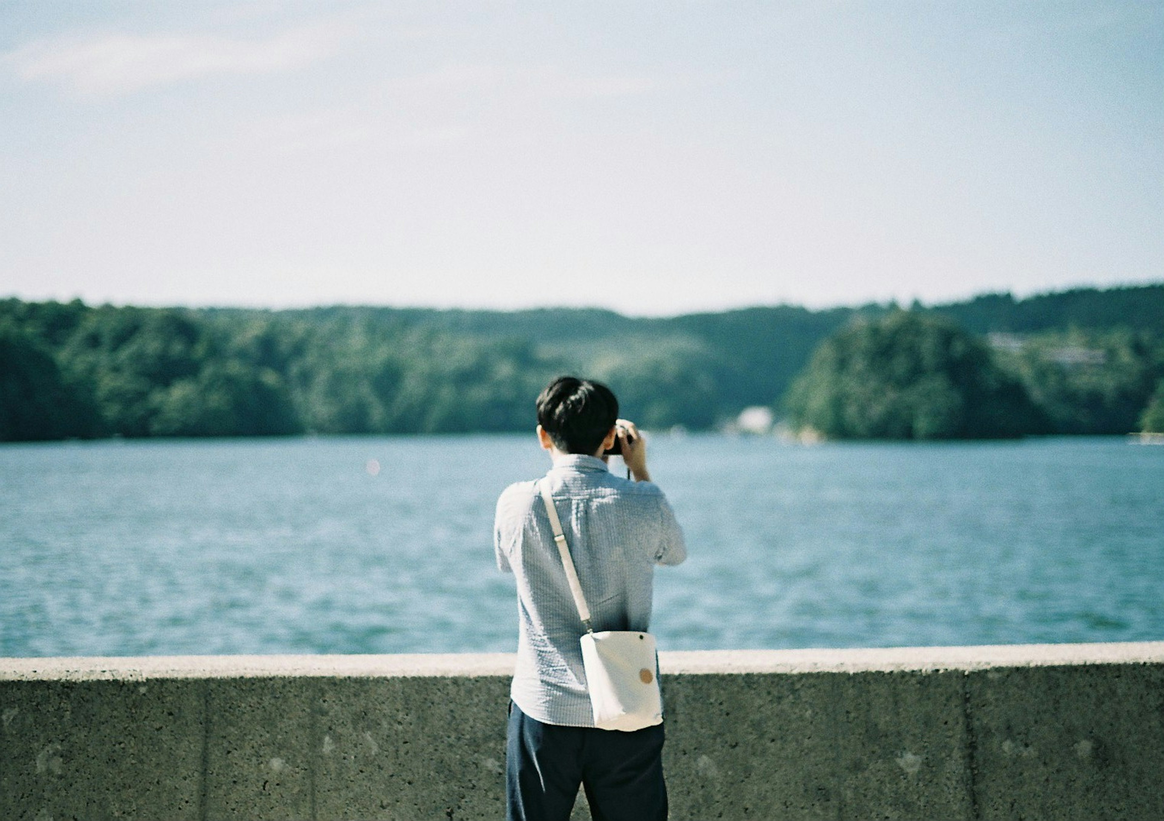 男性が湖の前で写真を撮っている風景