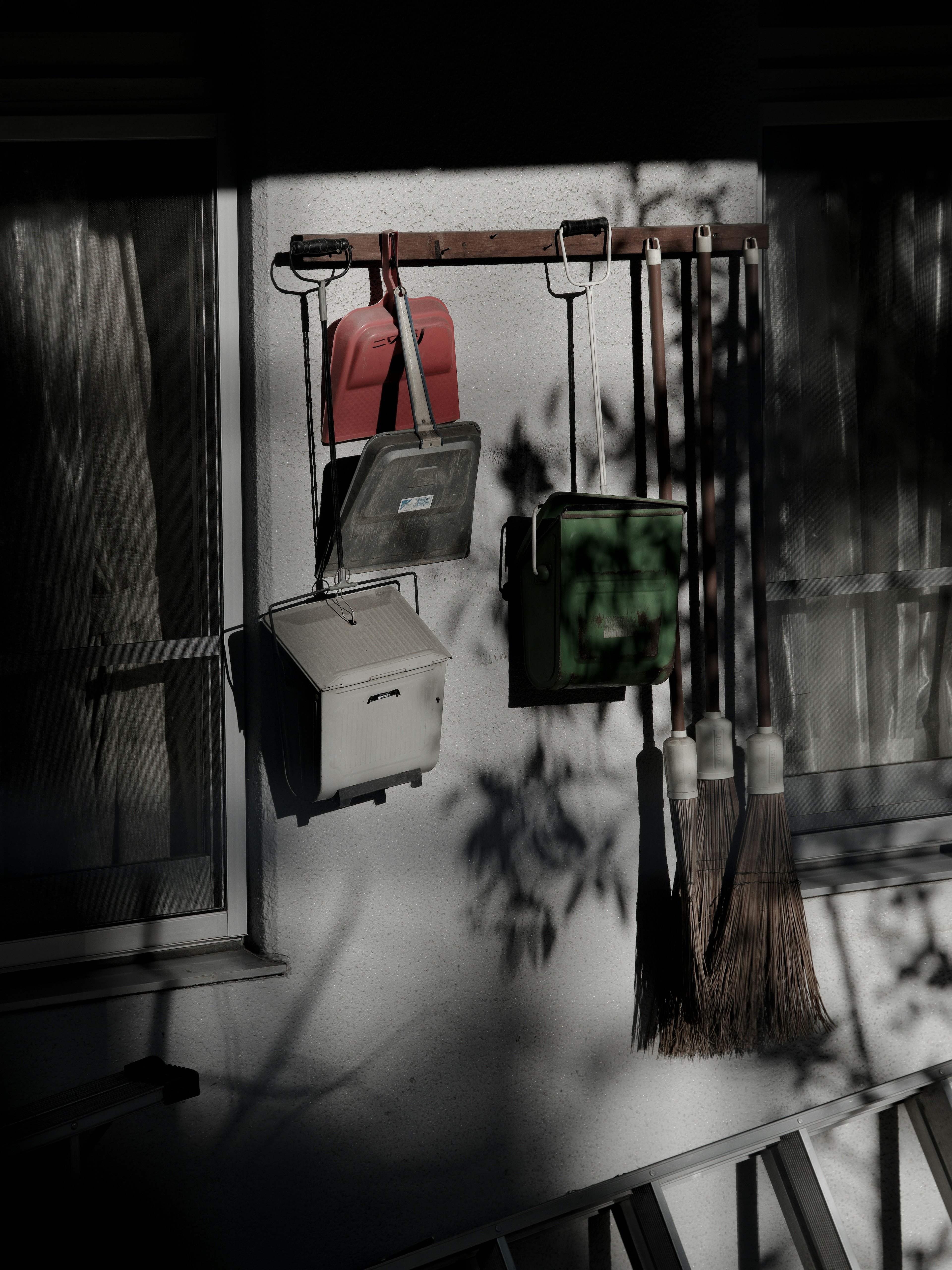 Shadowed wall with hanging red bags and green box