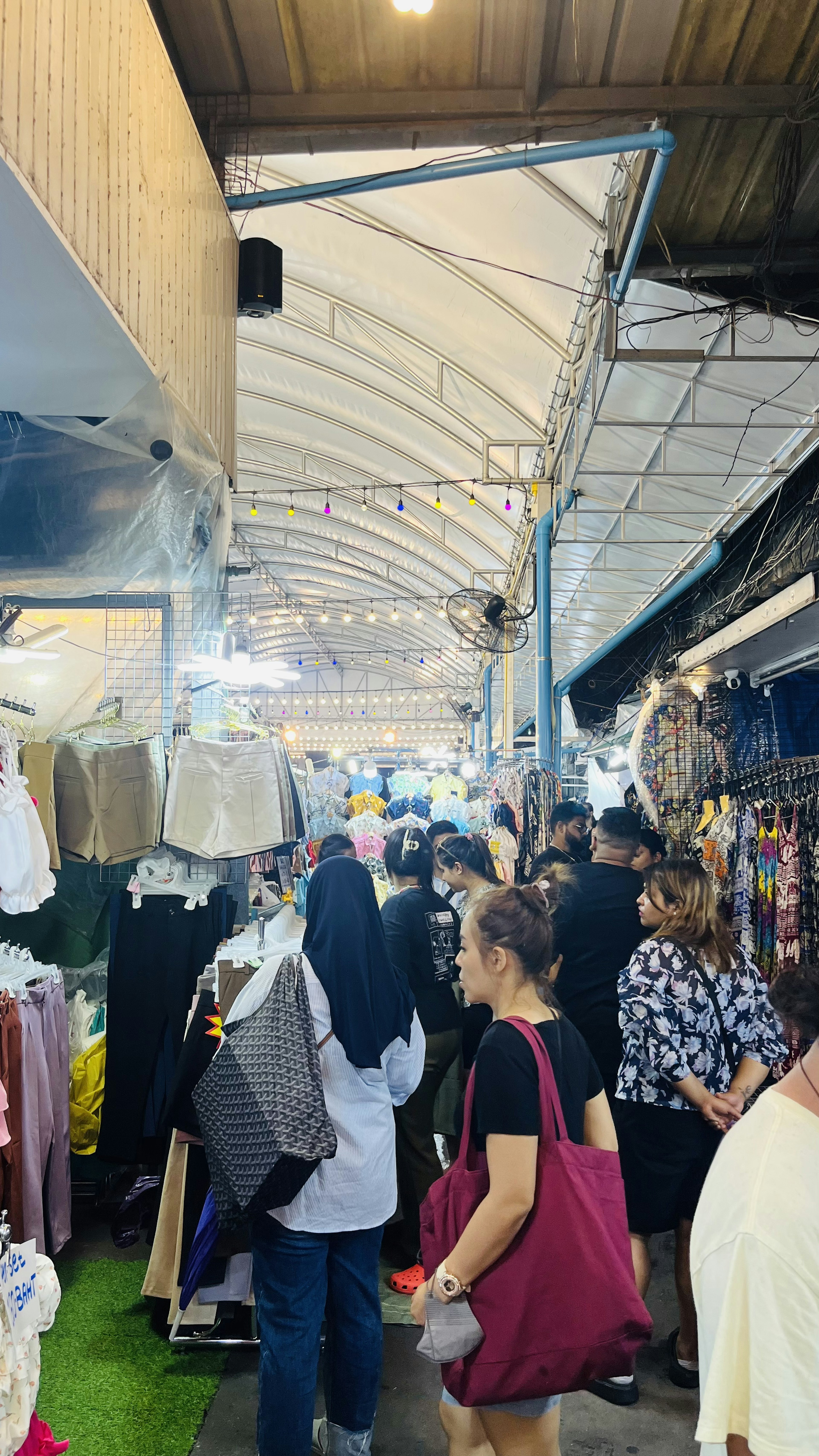 Corridoio di mercato affollato con persone che fanno shopping e sfogliano le bancarelle