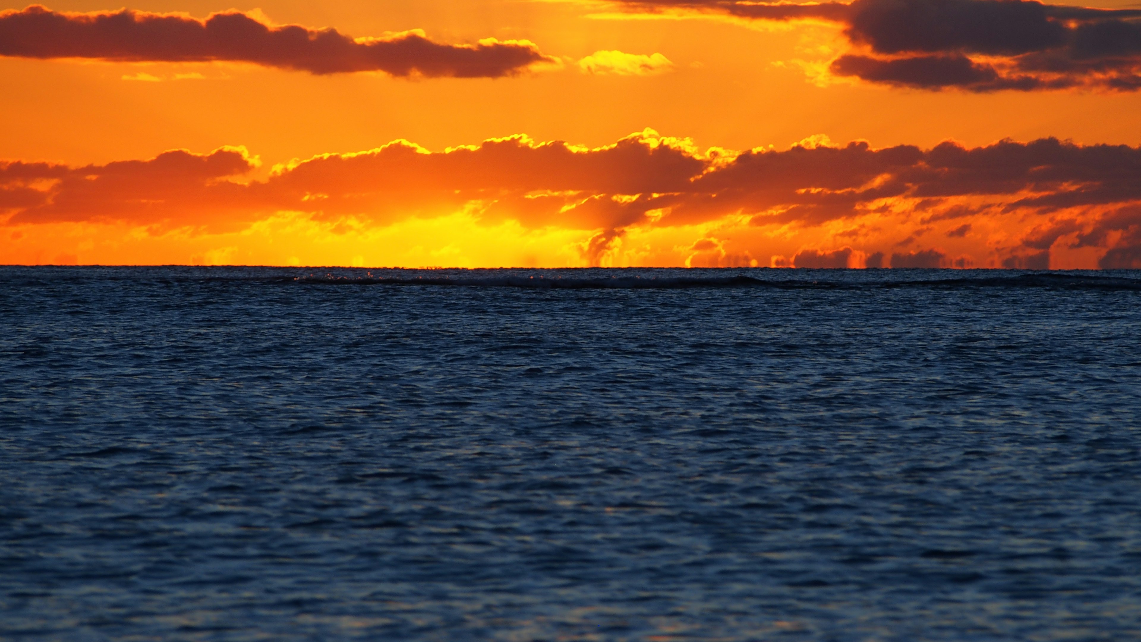 Atardecer naranja sobre el horizonte oceánico con superficie marina azul