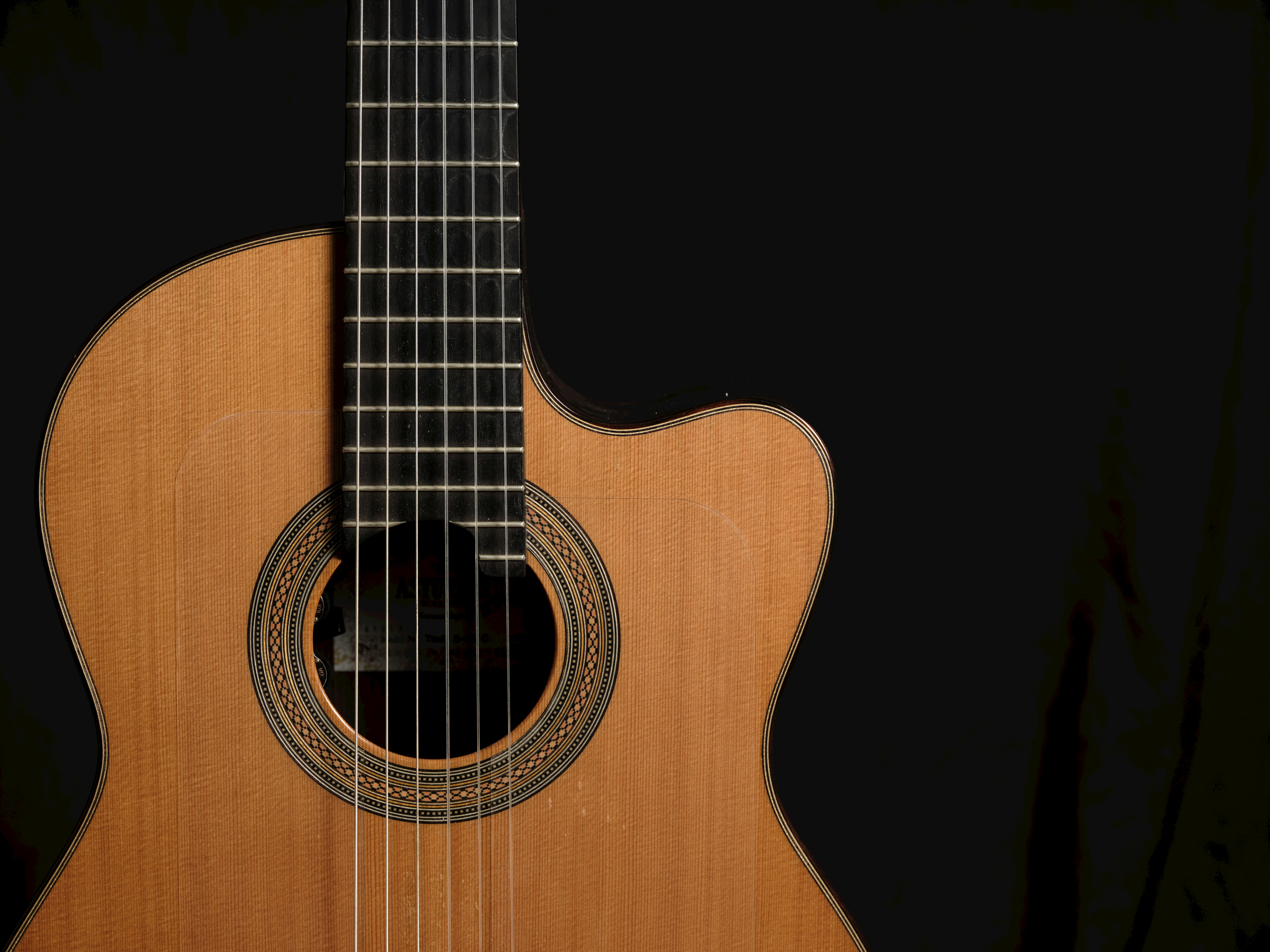 Wooden acoustic guitar body against a black background