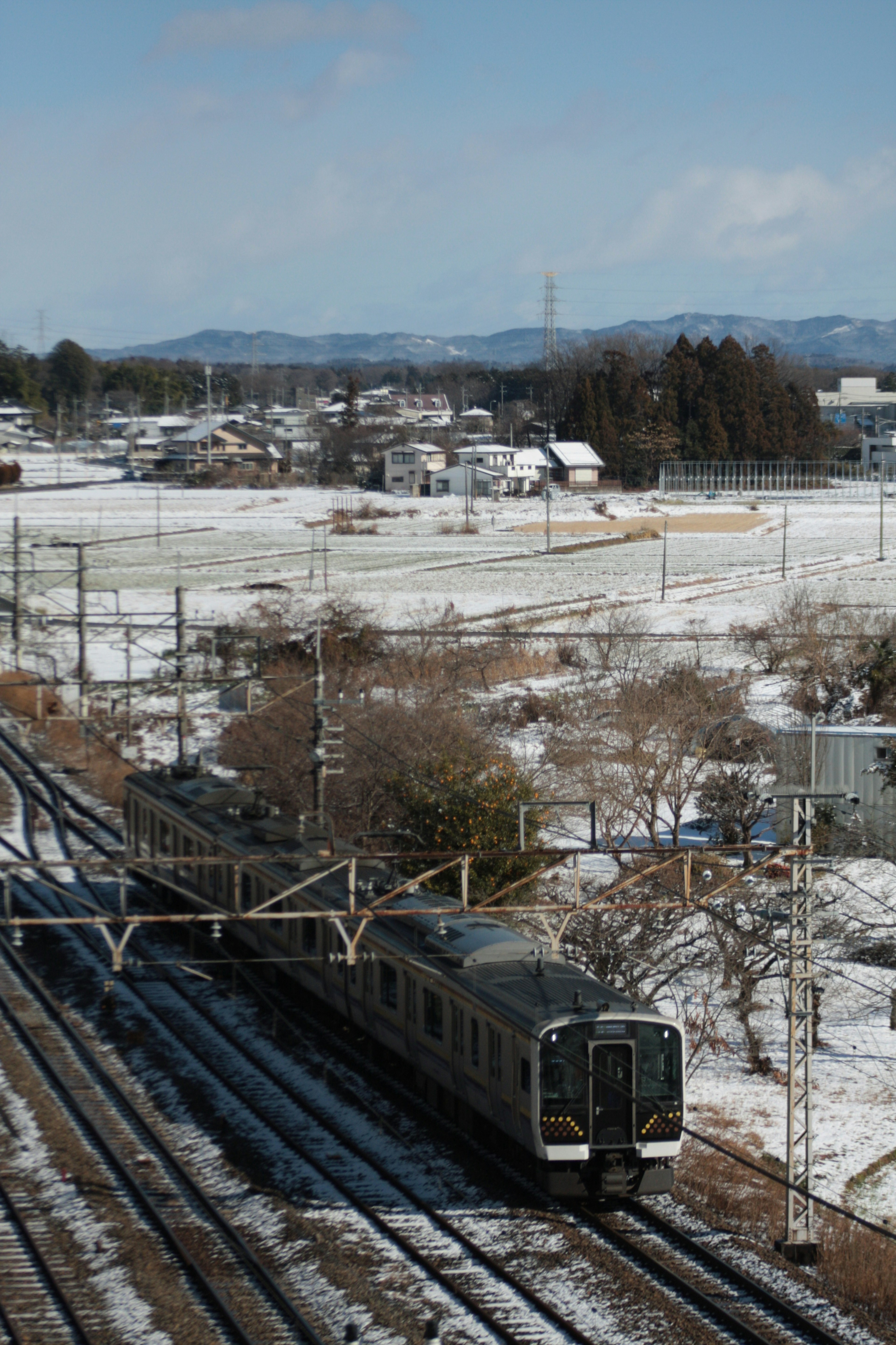 รถไฟที่วิ่งผ่านภูมิทัศน์ที่มีหิมะและภูเขาในพื้นหลัง