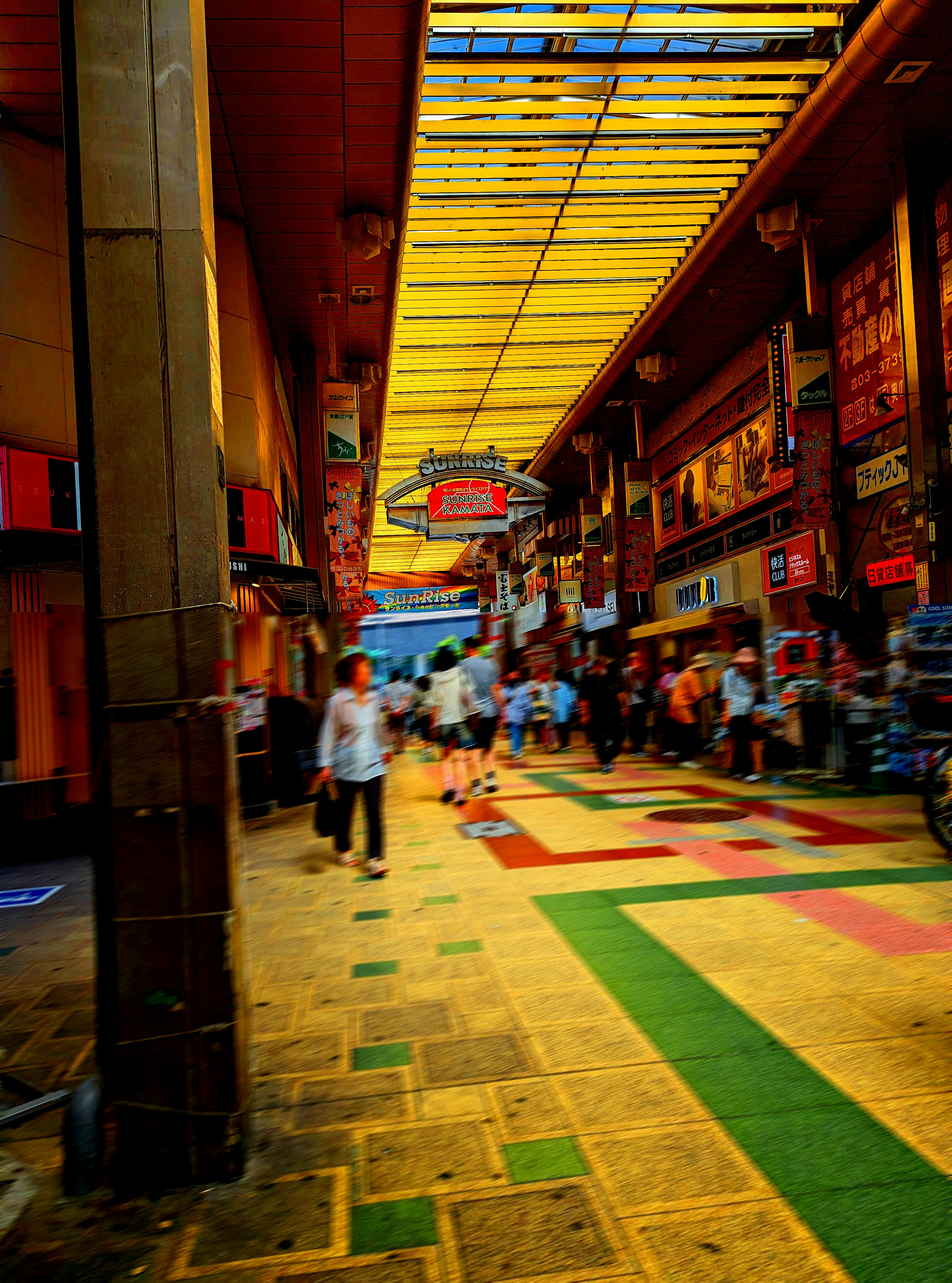 Calle comercial concurrida con personas caminando y suelo colorido