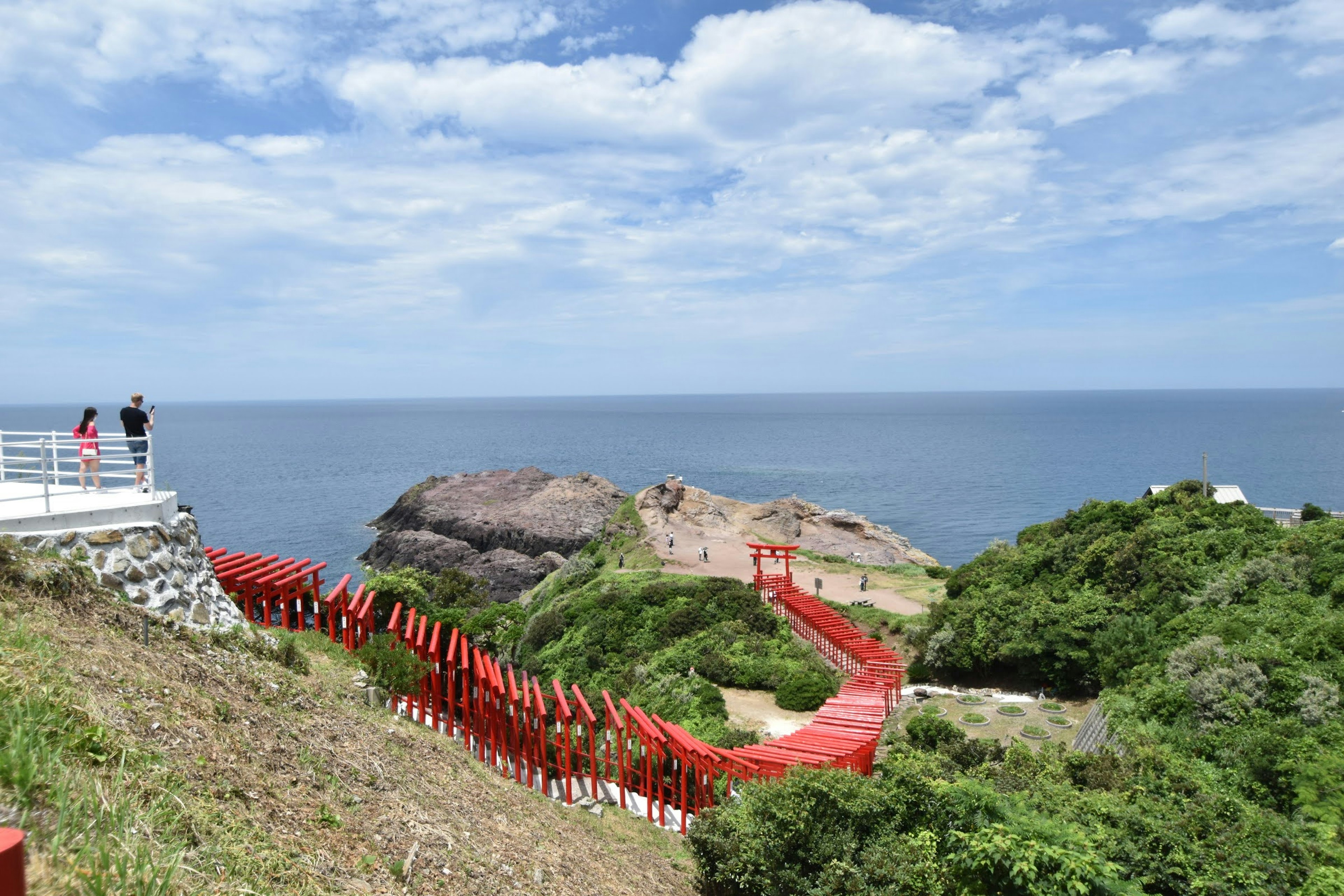 Vista panoramica di un sentiero rosso che conduce alla costa e cielo blu