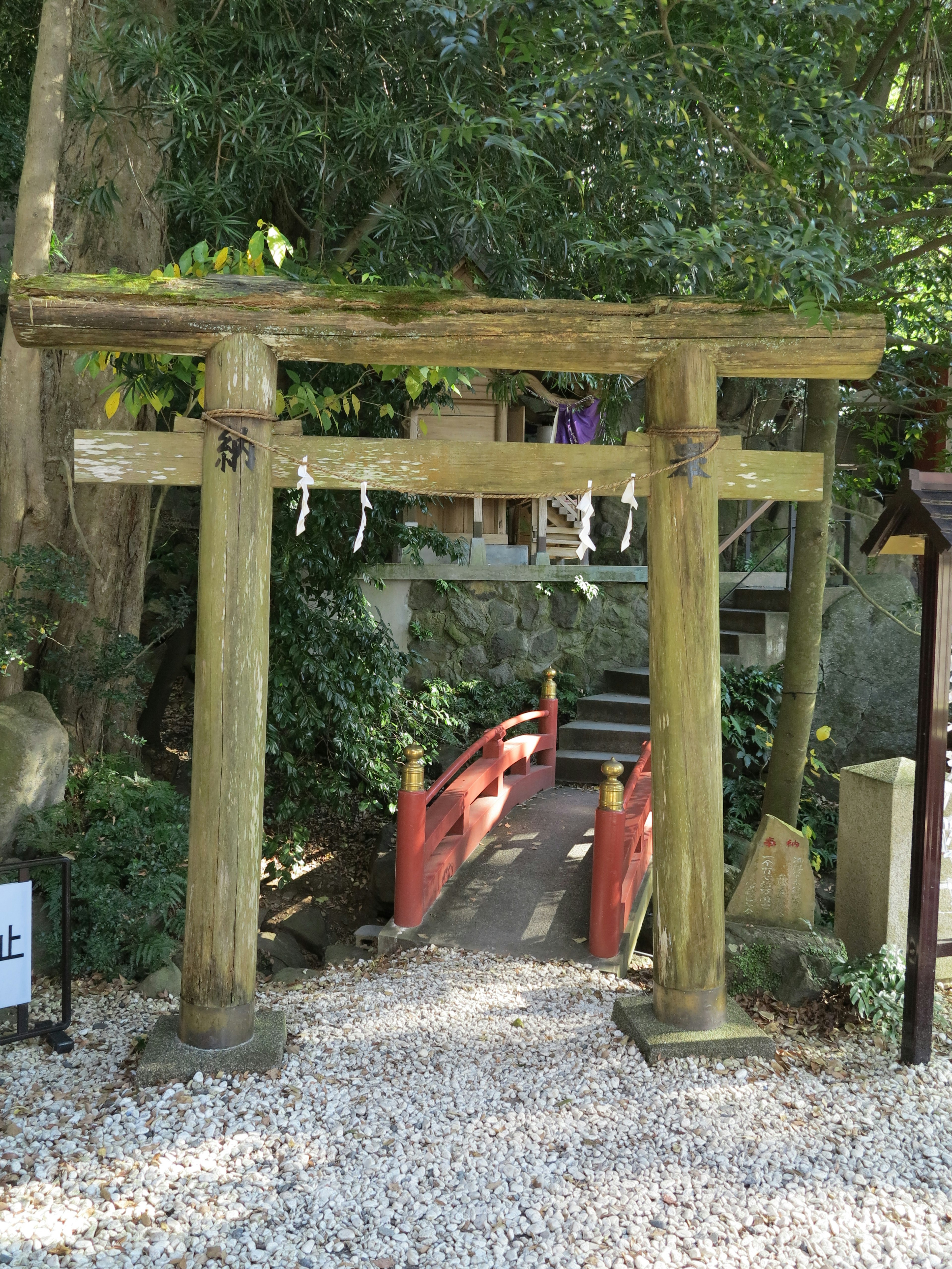 Un paesaggio sereno con un torii e un ponte rosso circondato da vegetazione lussureggiante