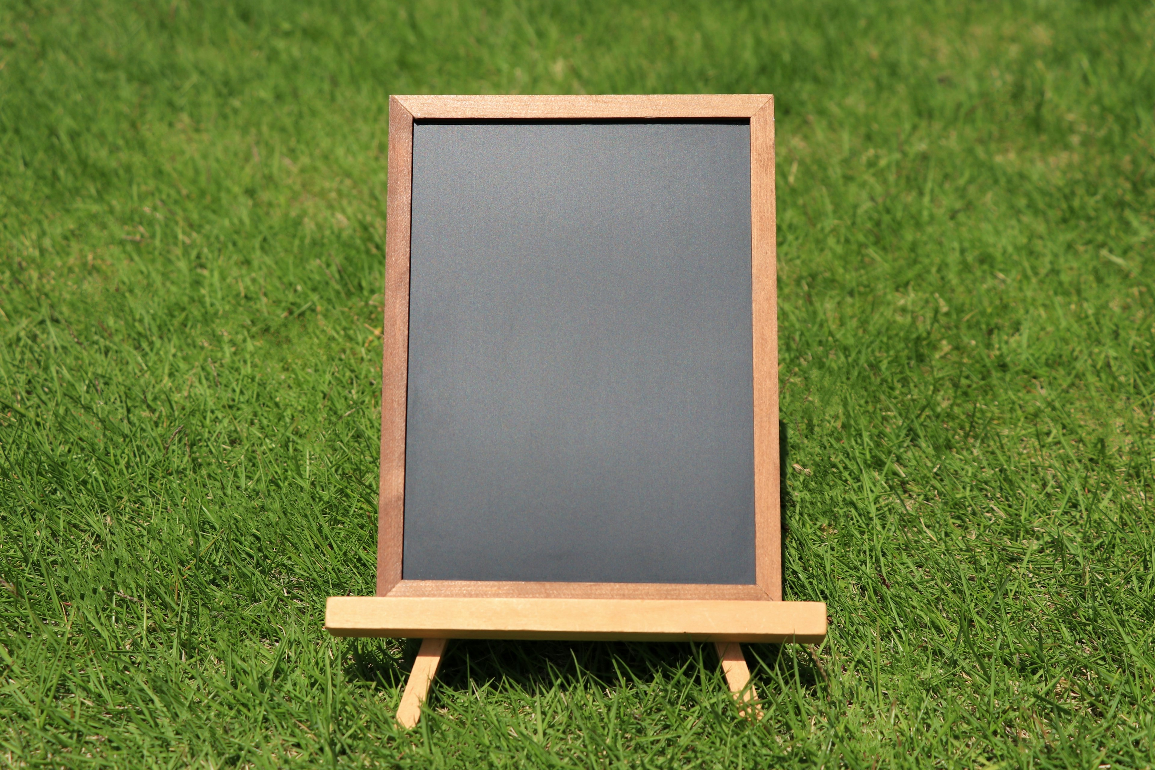 Un tableau noir encadré en bois posé sur de l'herbe verte