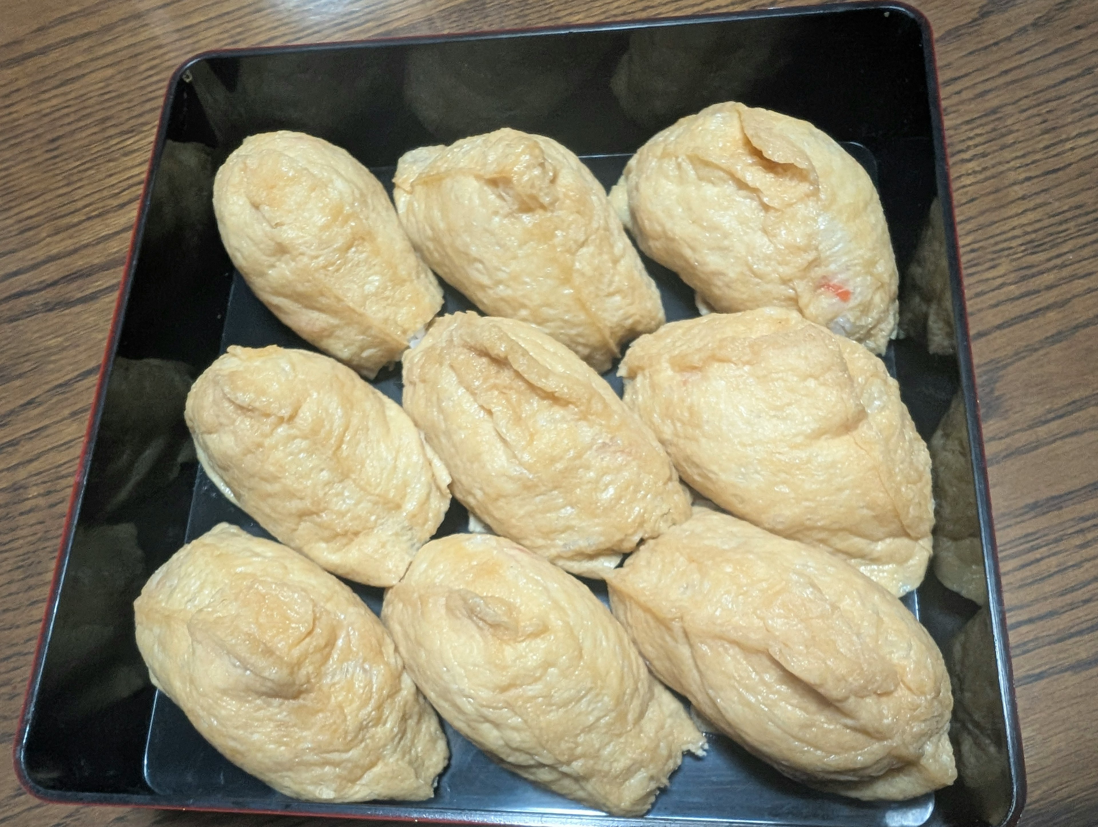 Ten pieces of fried tofu pouches arranged in a black tray