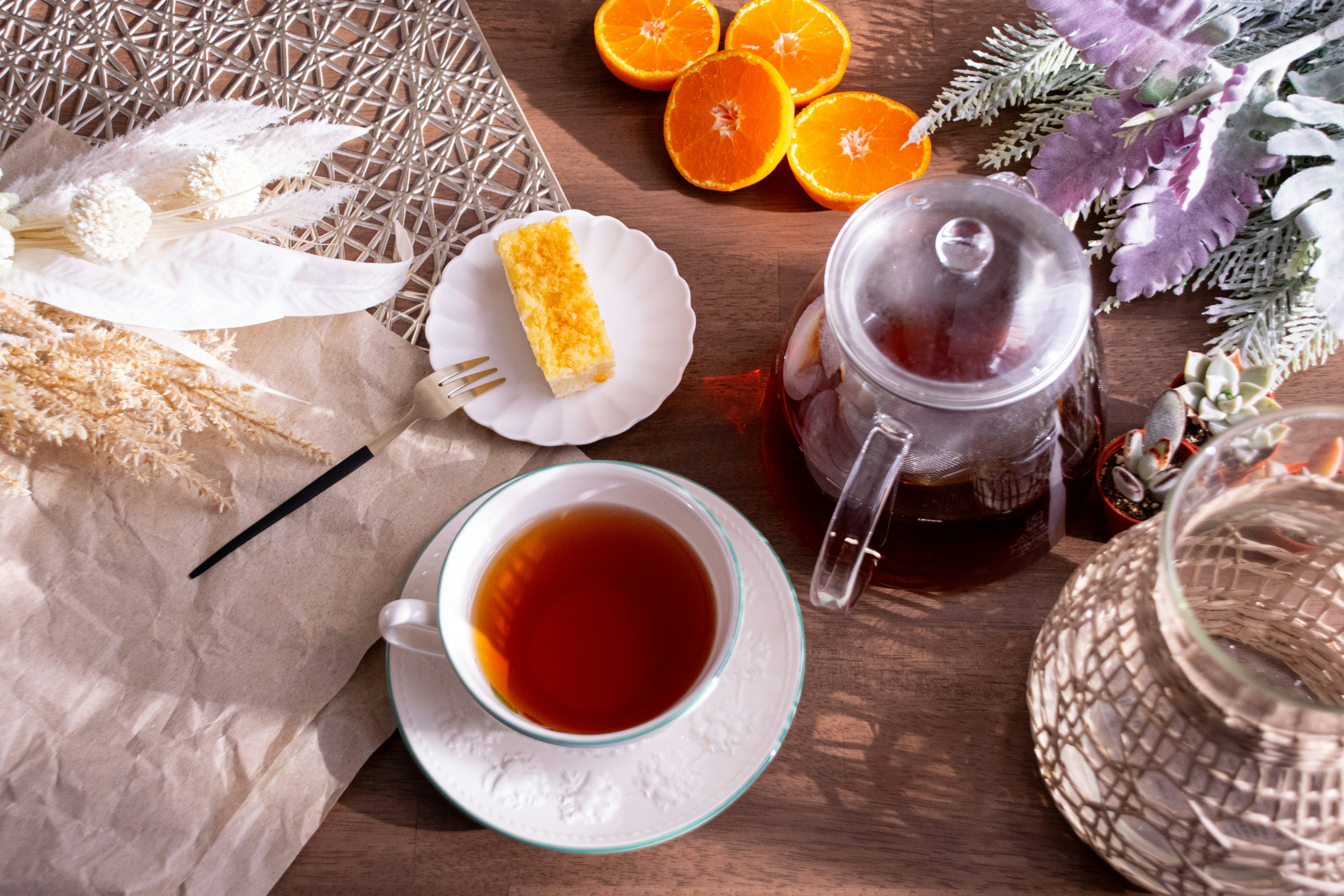 Une table avec du thé et un gâteau accompagnés d'oranges et de plantes sèches