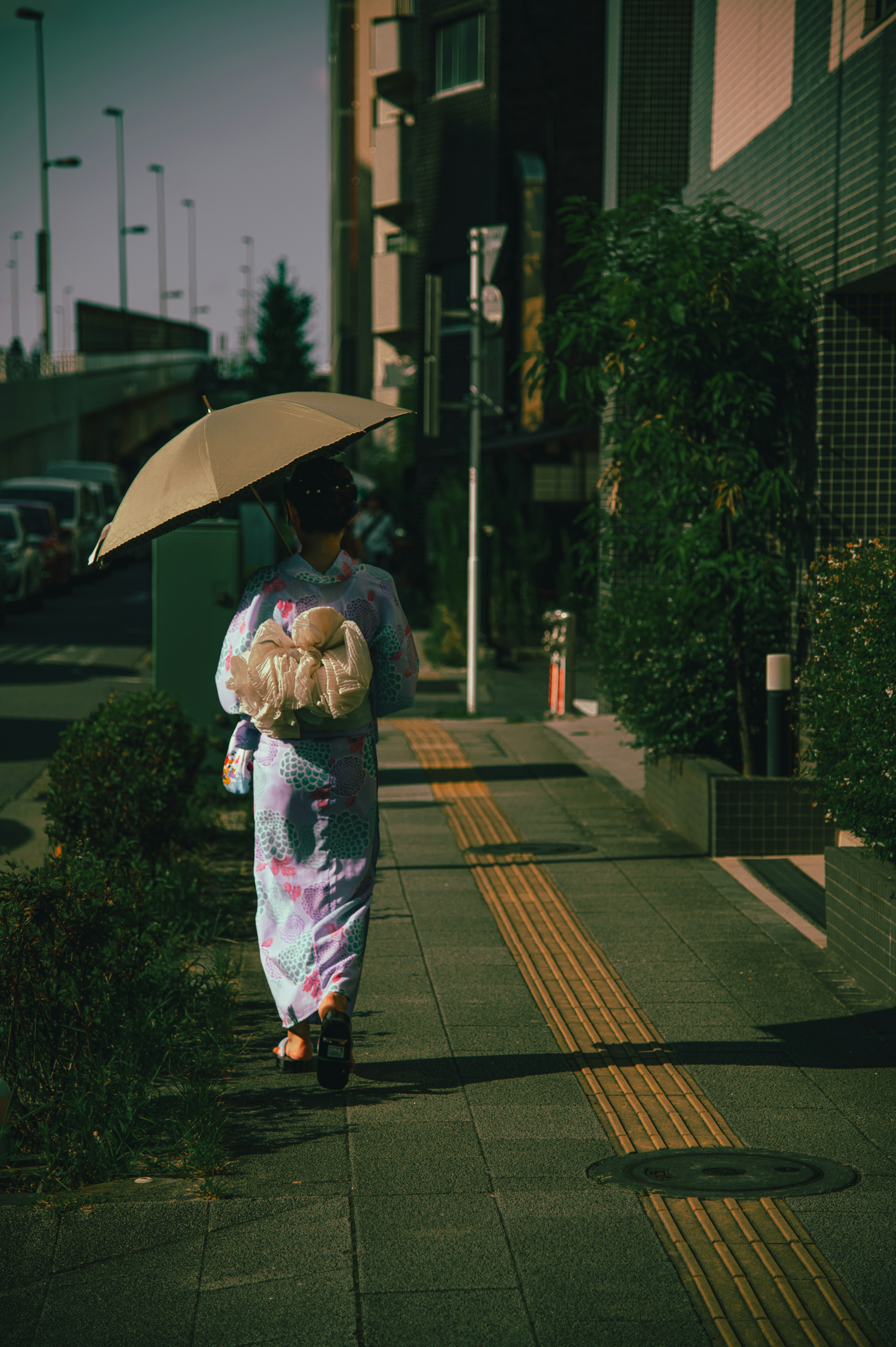 Frau, die mit einem Regenschirm in einem Kimono in einer städtischen Umgebung geht