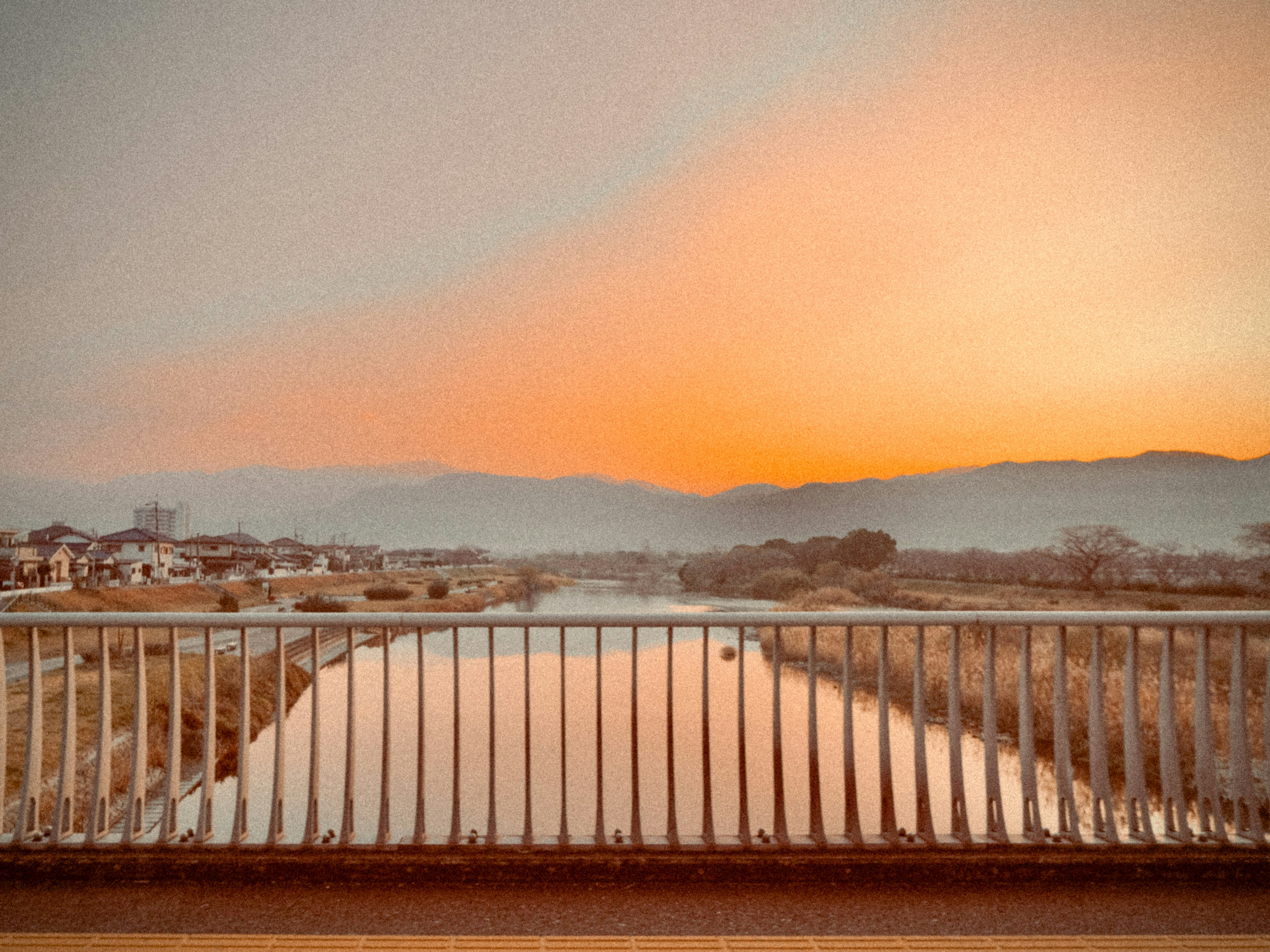 Vue pittoresque d'une rivière au coucher du soleil avec un garde-corps de pont au premier plan