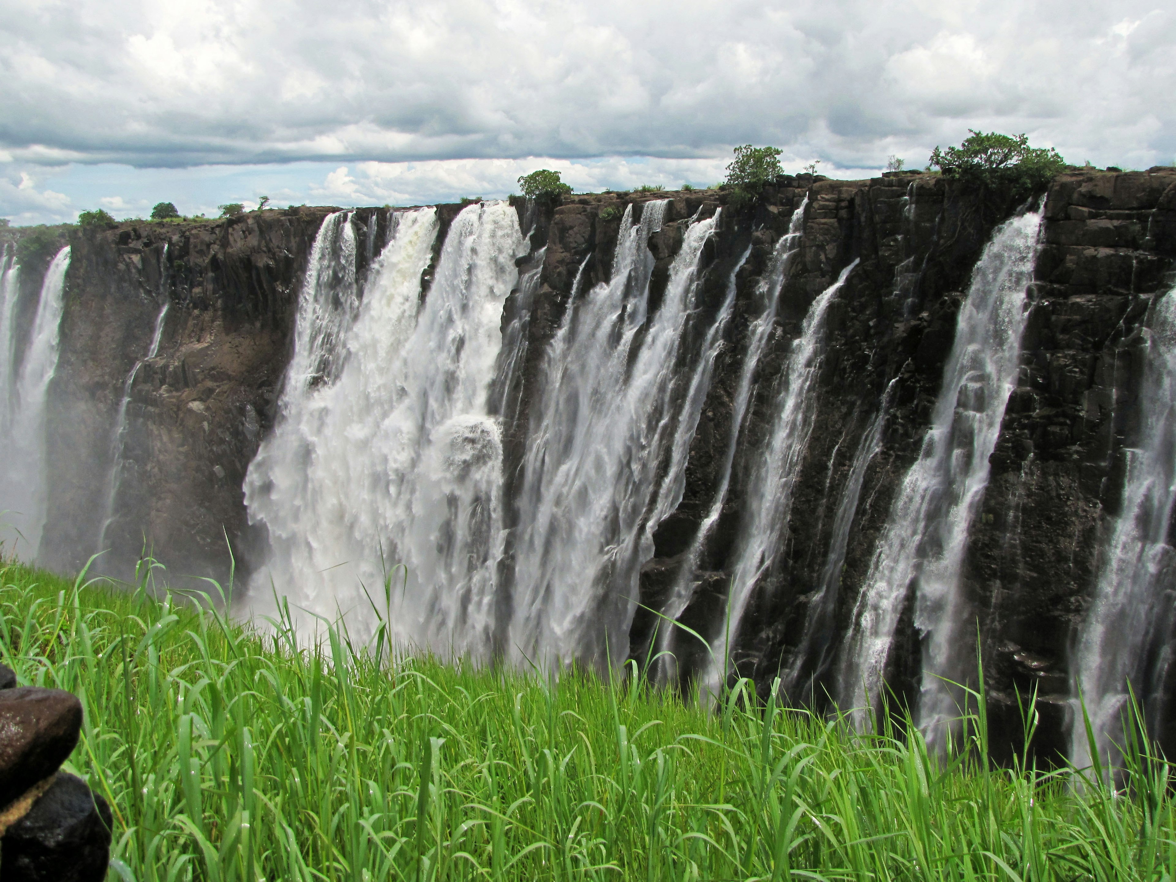 Ein majestätischer Wasserfall, der über Klippen stürzt, mit üppigem grünem Gras im Vordergrund