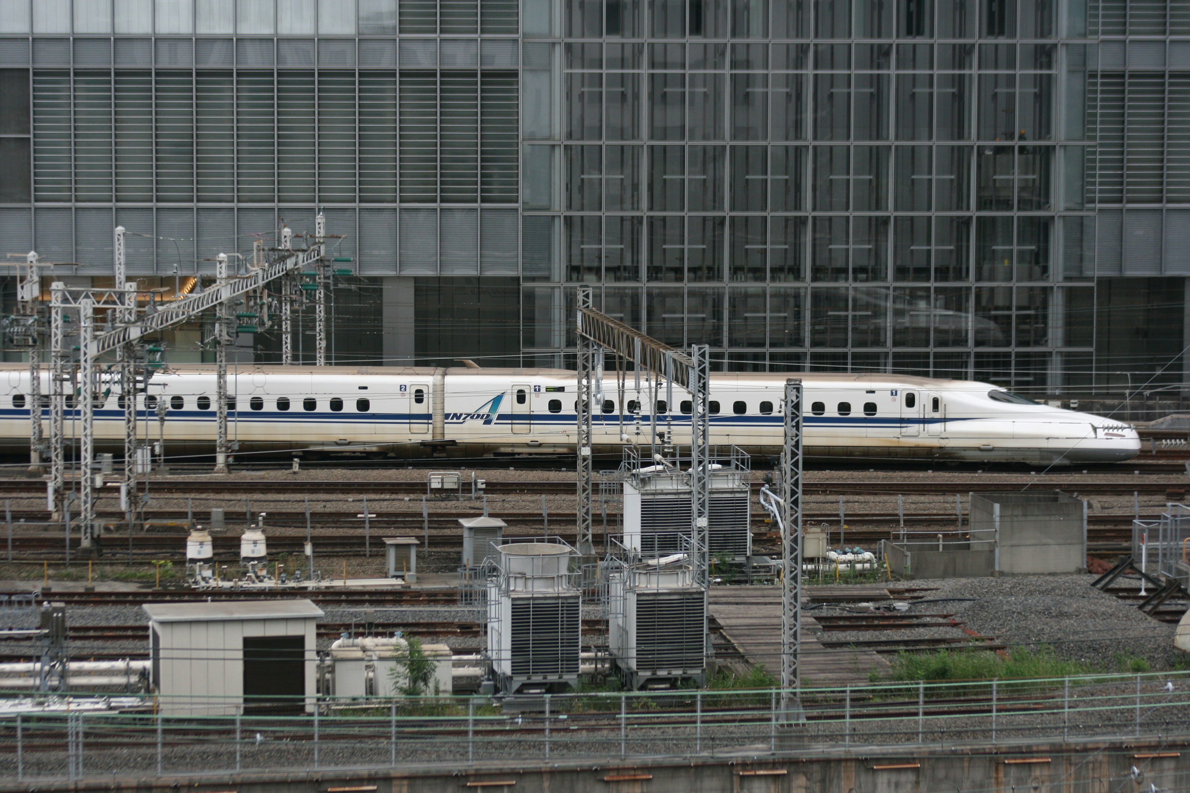 Shinkansen train parked at a station with modern buildings in the background