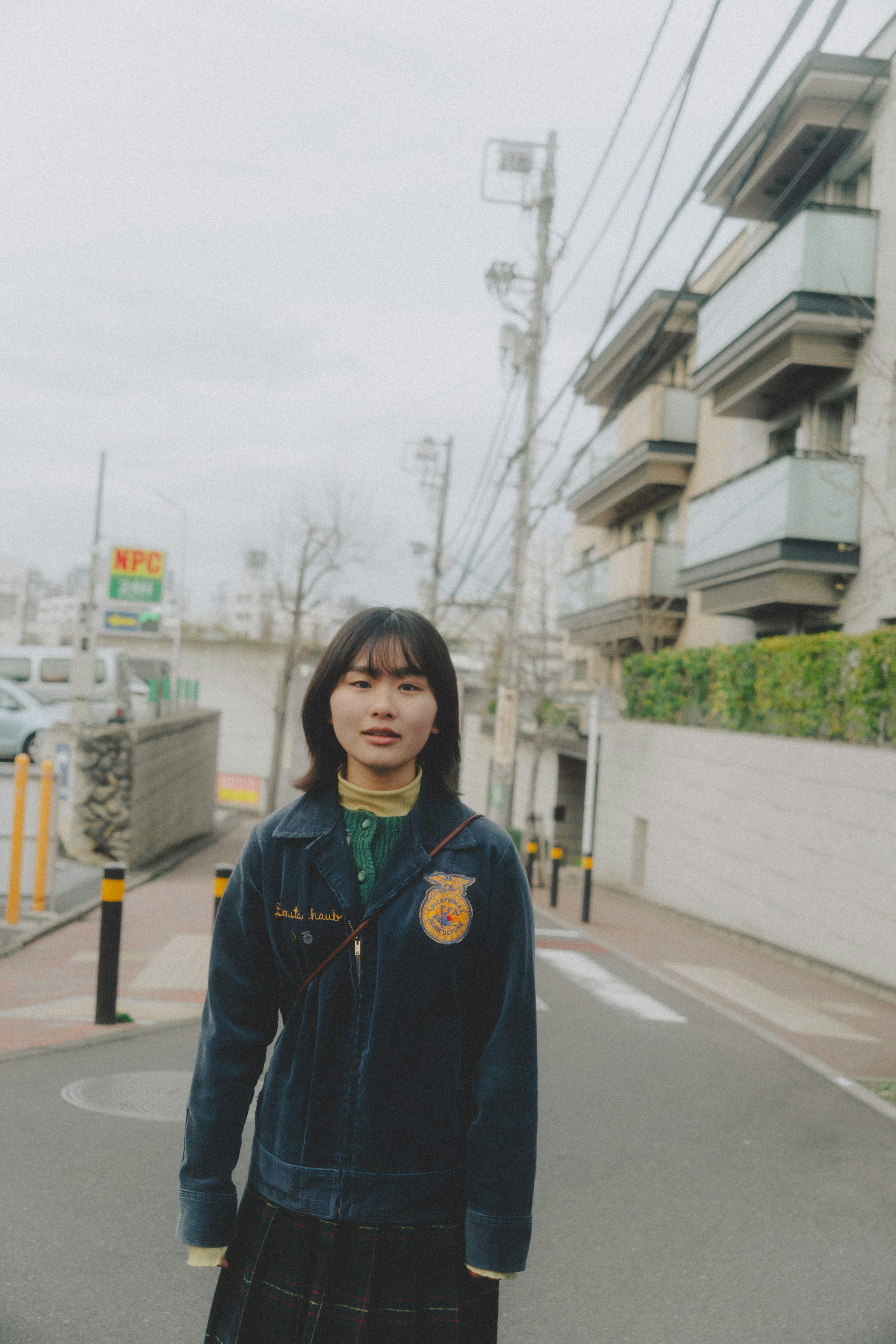 Young woman standing on a city street wearing a fabric jacket and skirt