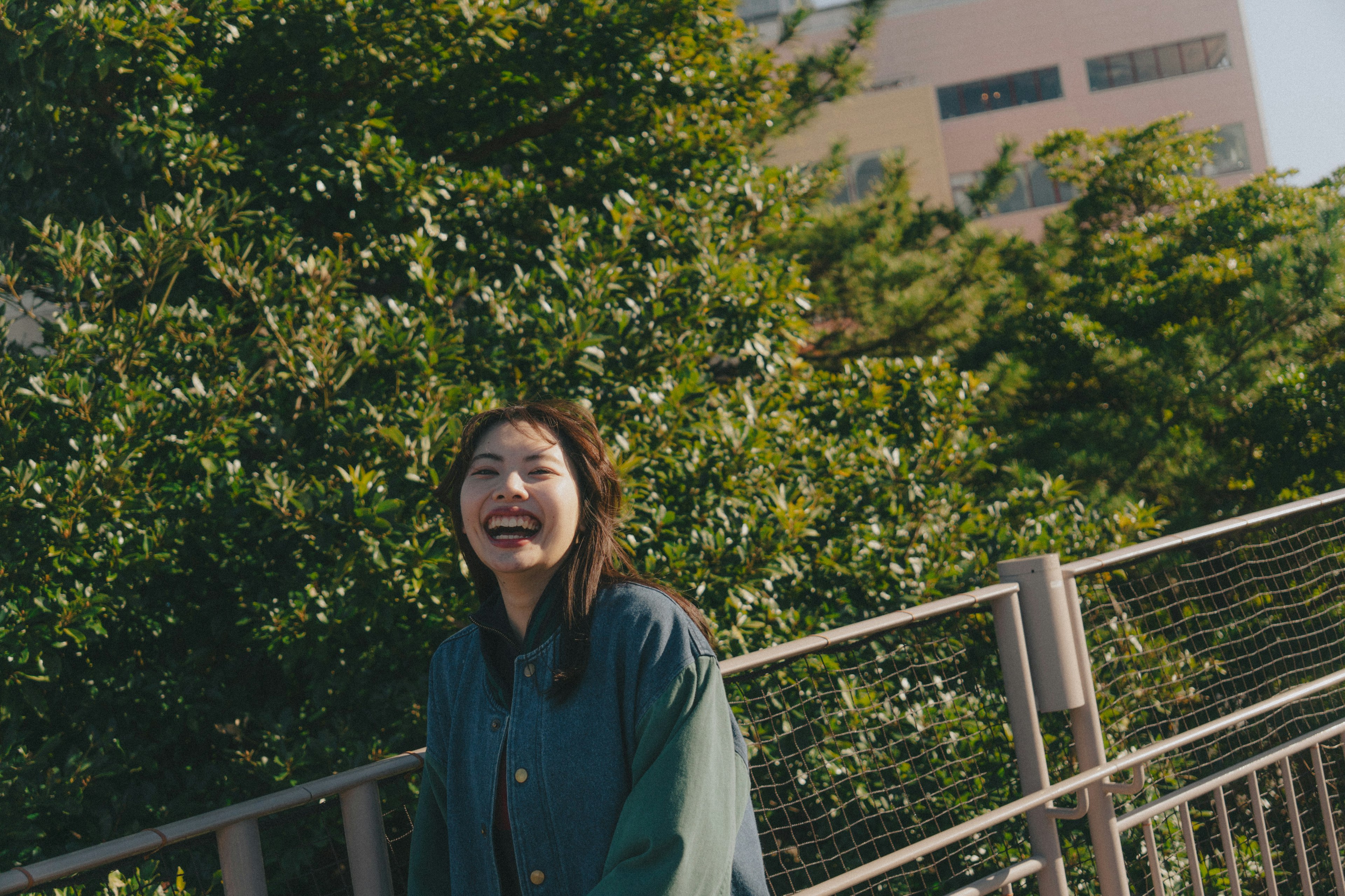 A smiling woman standing amidst green foliage in a park