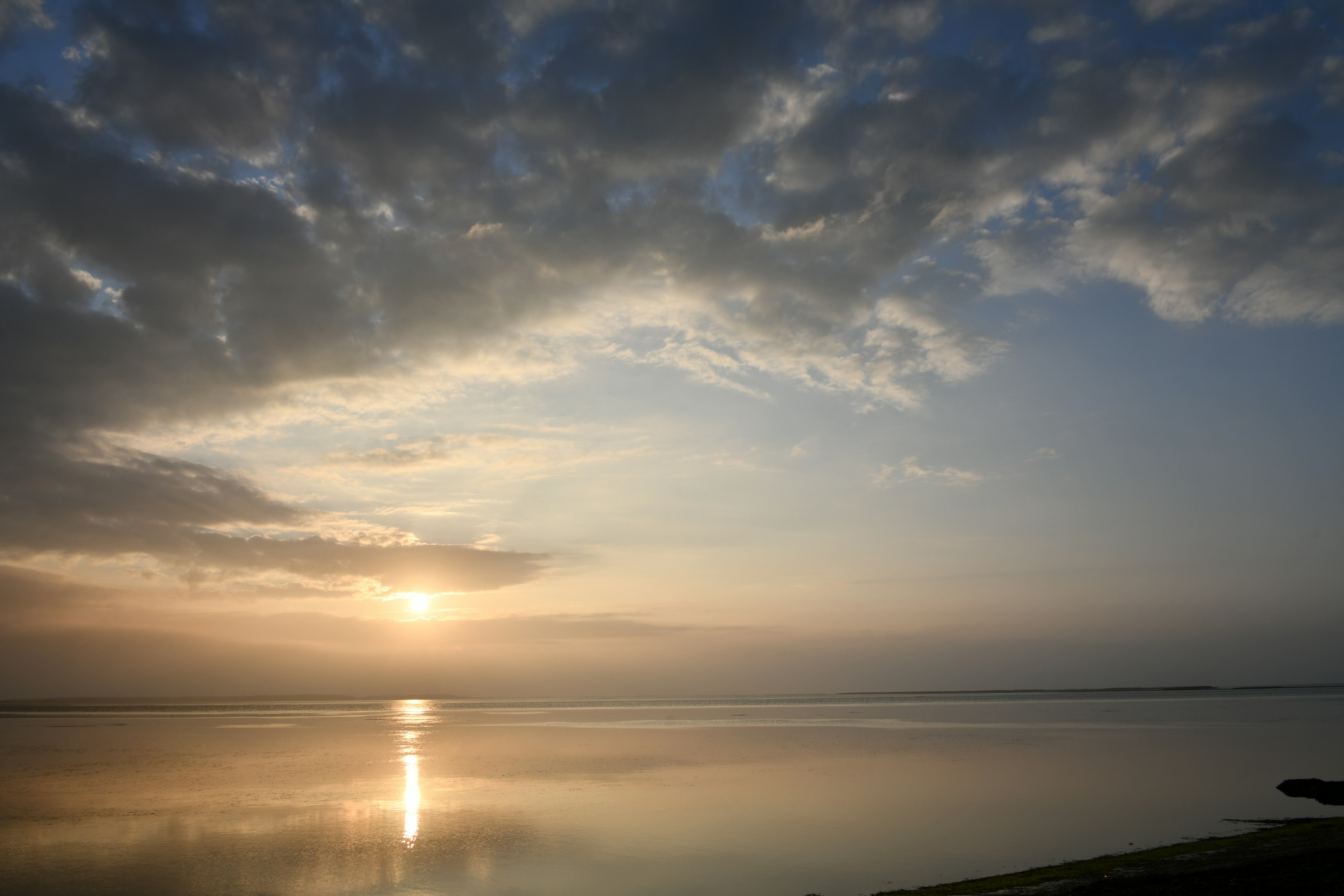 Tramonto su un lago calmo che riflette nuvole e superficie dell'acqua