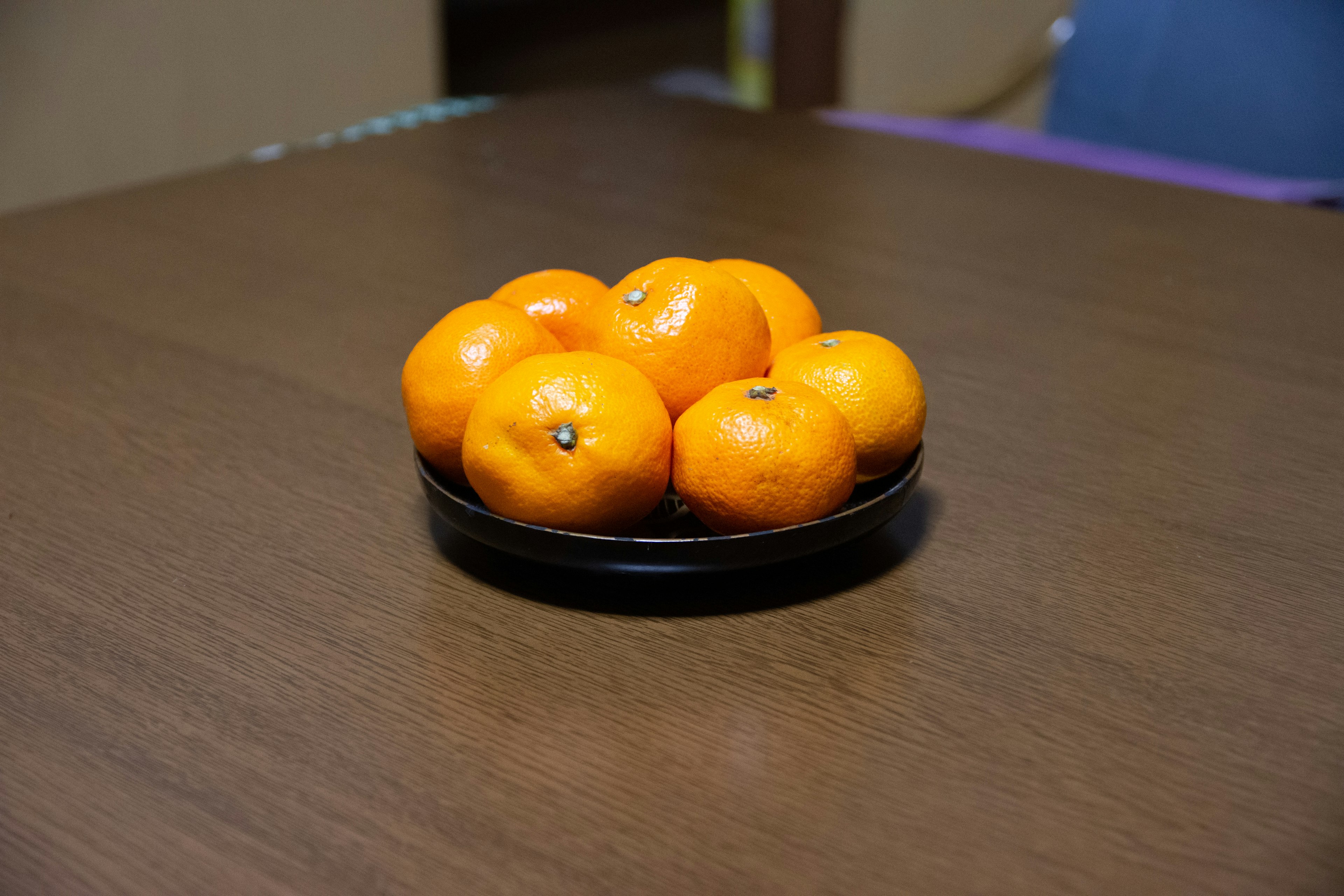 Un tazón de naranjas sobre una mesa de madera