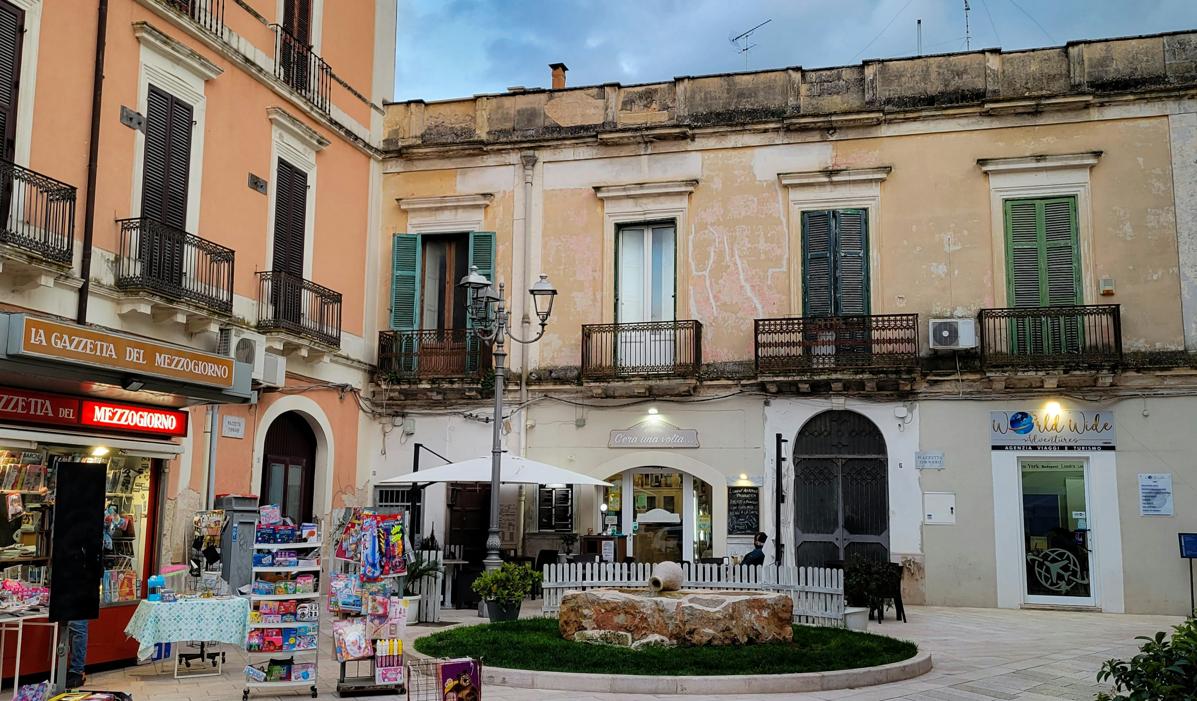 Plaza con edificios antiguos, fuente y terraza de café