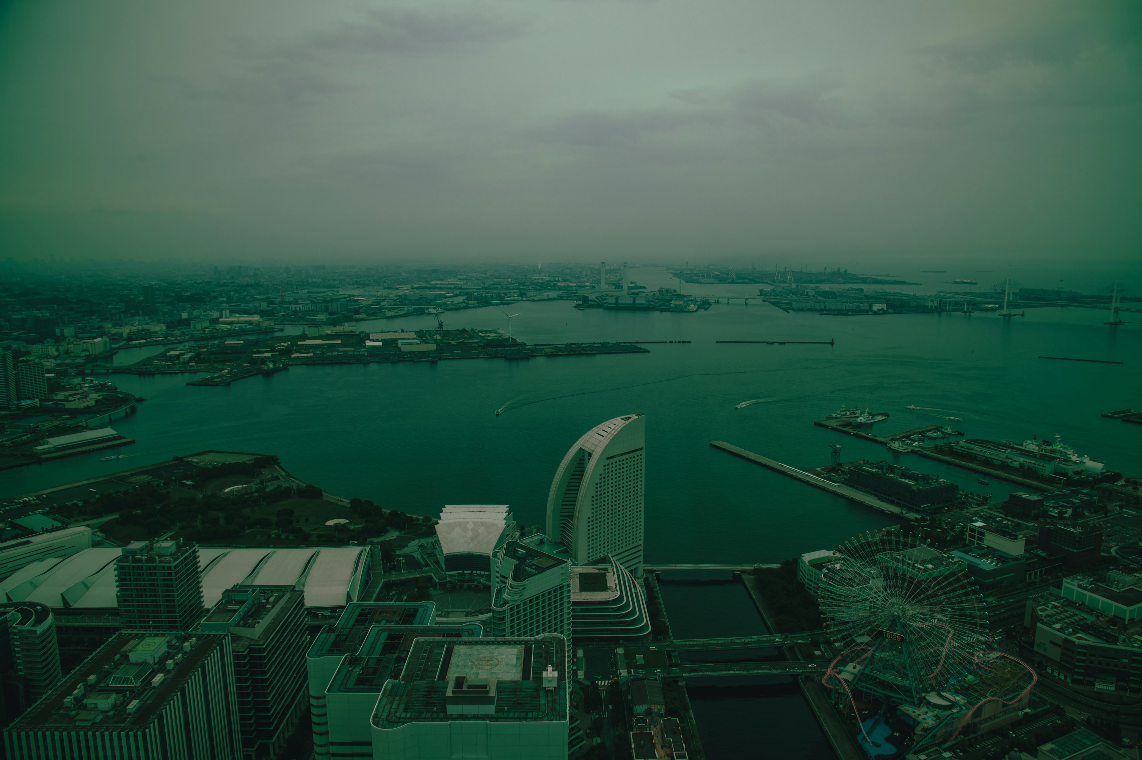 A green-tinged view of the sea and cityscape from a skyscraper