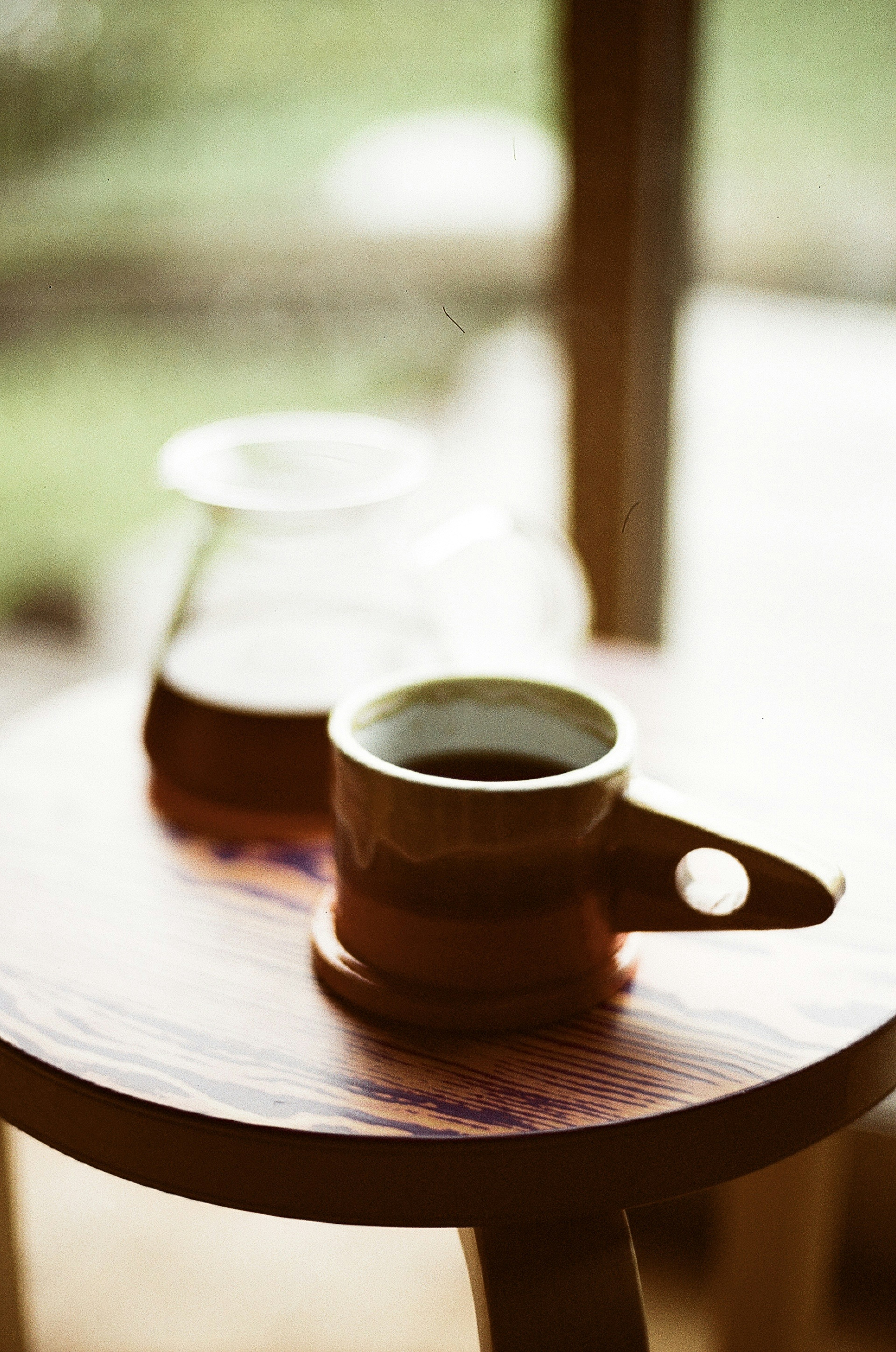 Une tasse de café et une carafe en verre sur une table en bois