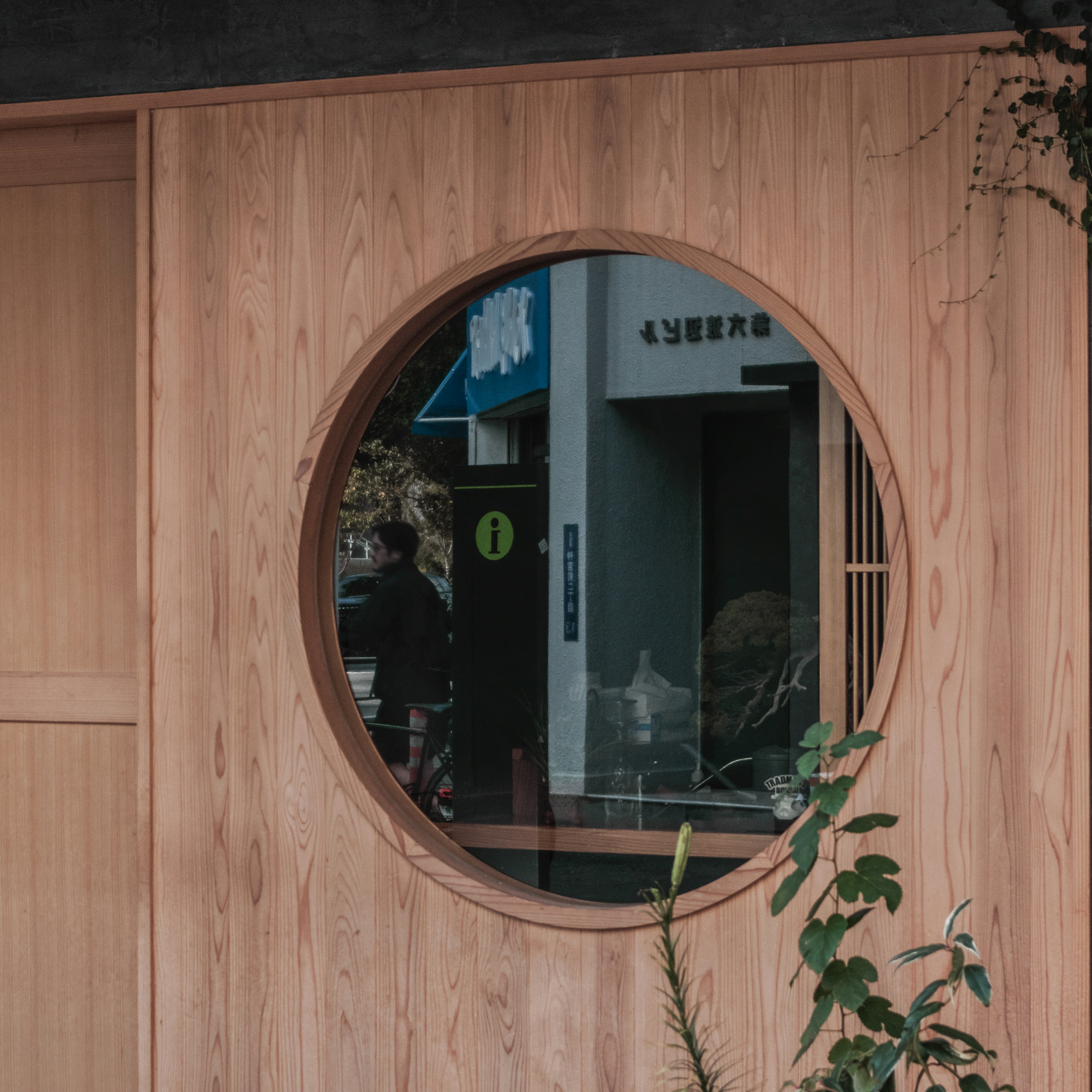 Espejo circular empotrado en una pared de madera que refleja una escena urbana