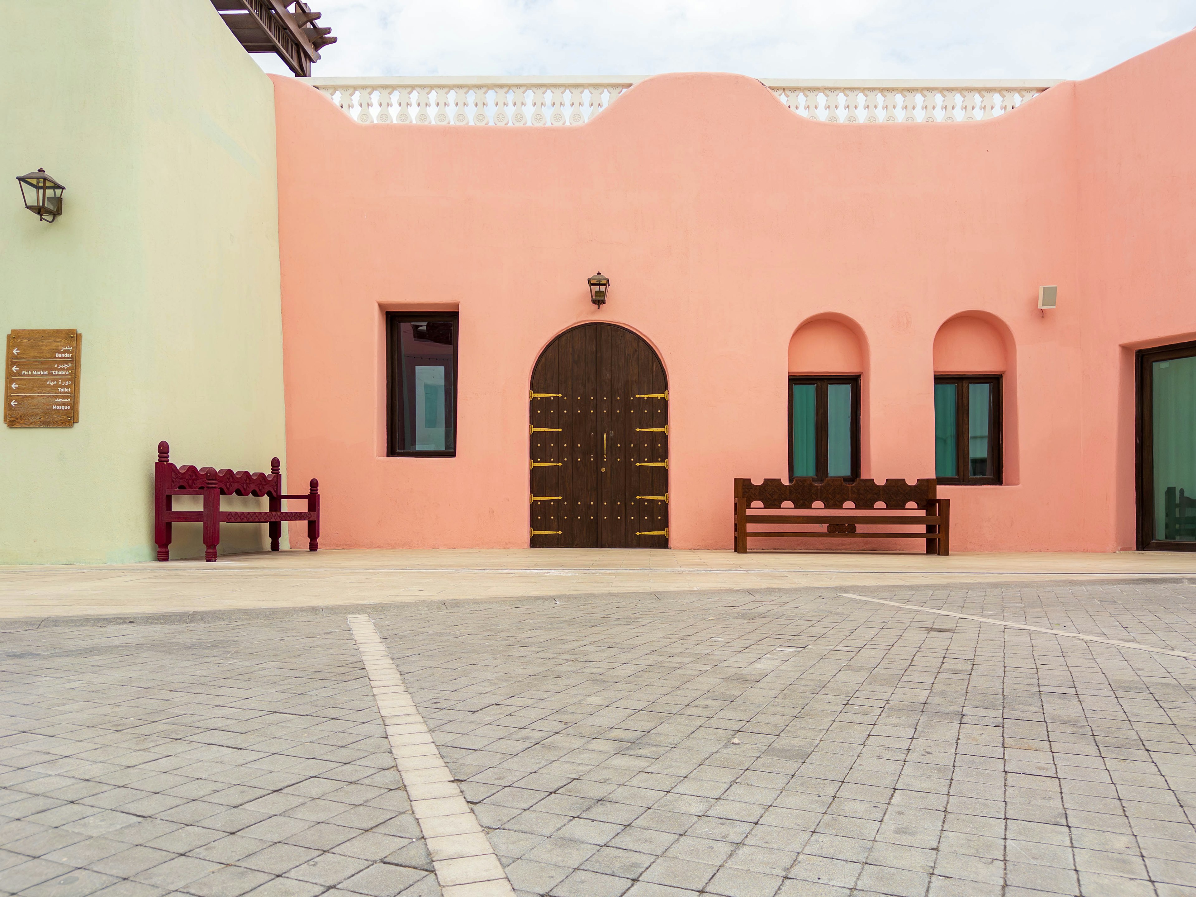 Exterior of a building with pink and green walls featuring an arched door and windows