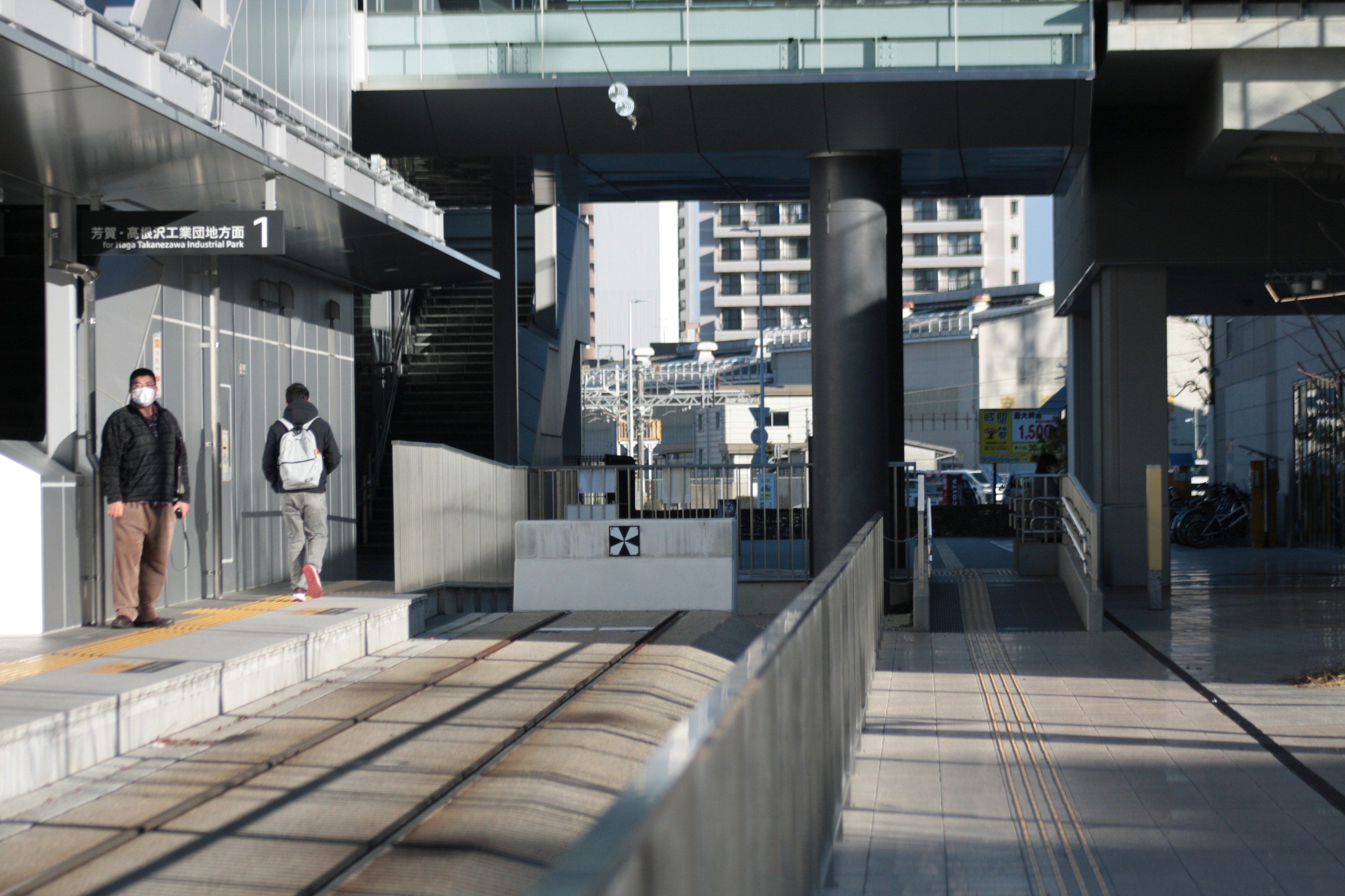 現代的な都市の駅の風景で、乗客が待っている様子が見られる