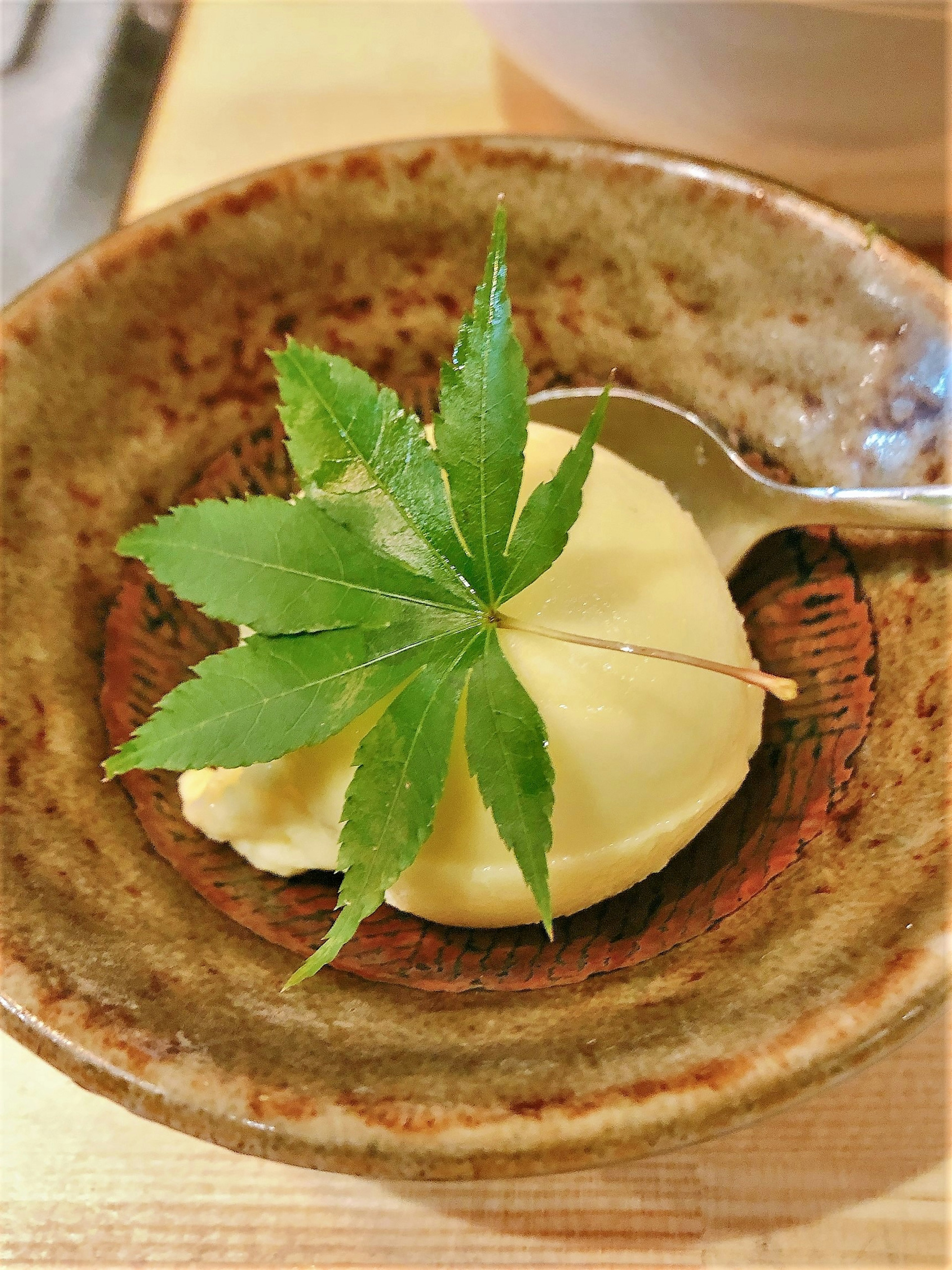 Dessert crémeux garni de feuilles vertes servi dans un plat en céramique