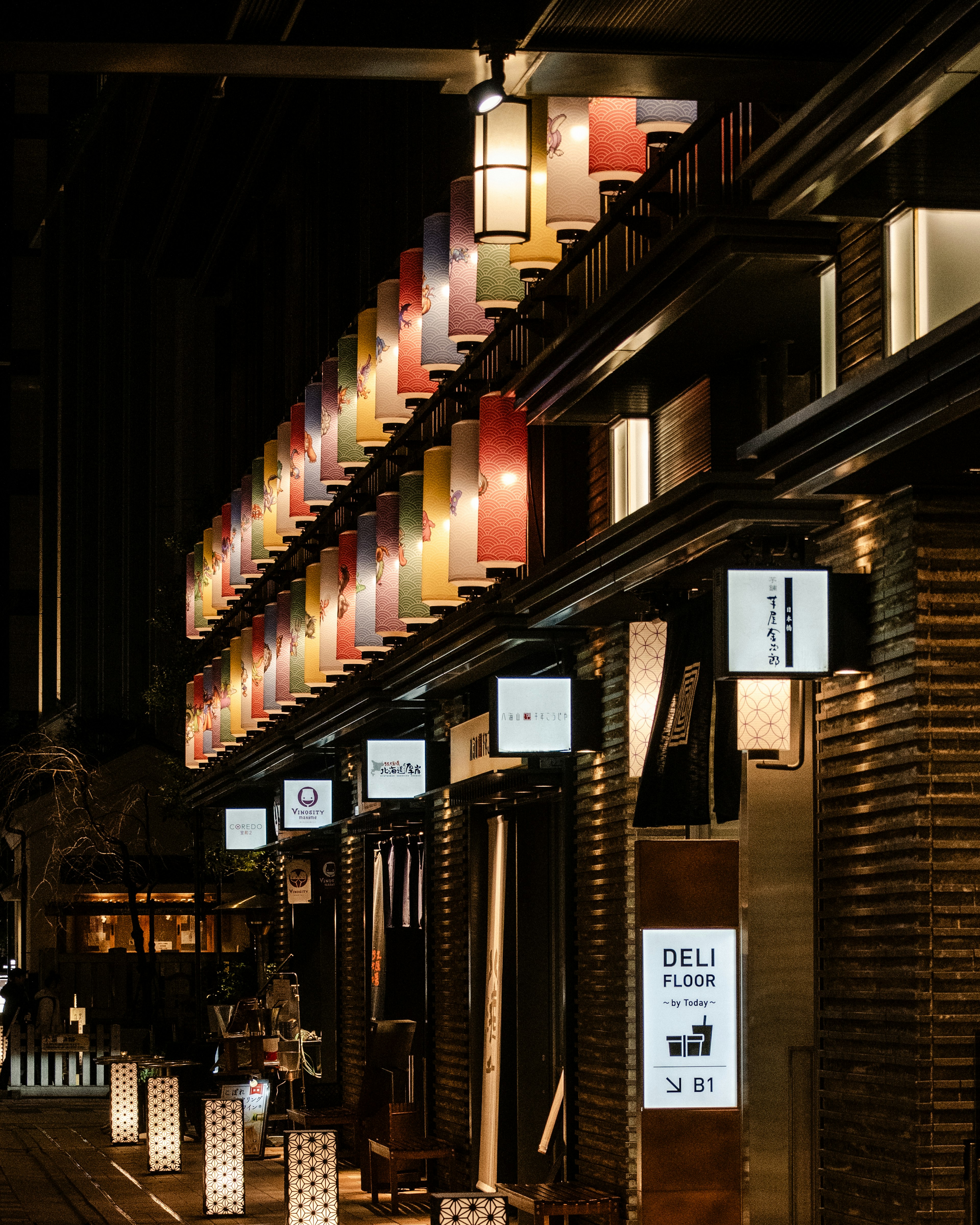 โคมไฟสีสันสดใสและป้ายร้านอาหารที่ตั้งเรียงรายในถนนเมืองในยามค่ำคืน